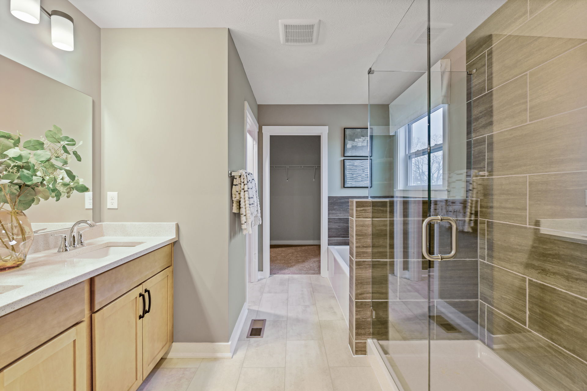 Modern bathroom featuring a glass shower, wooden vanity with dual sinks, and a neutral color palette for a spacious, contemporary look.