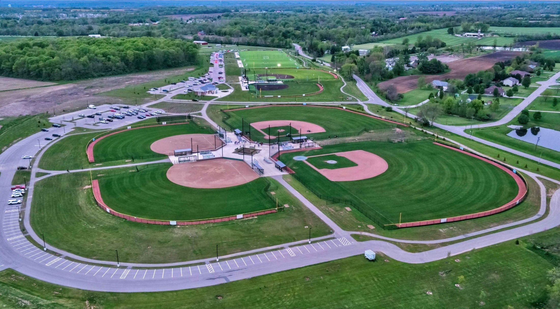 Aerial view of a large sports complex featuring multiple baseball and soccer fields surrounded by lush greenery.
