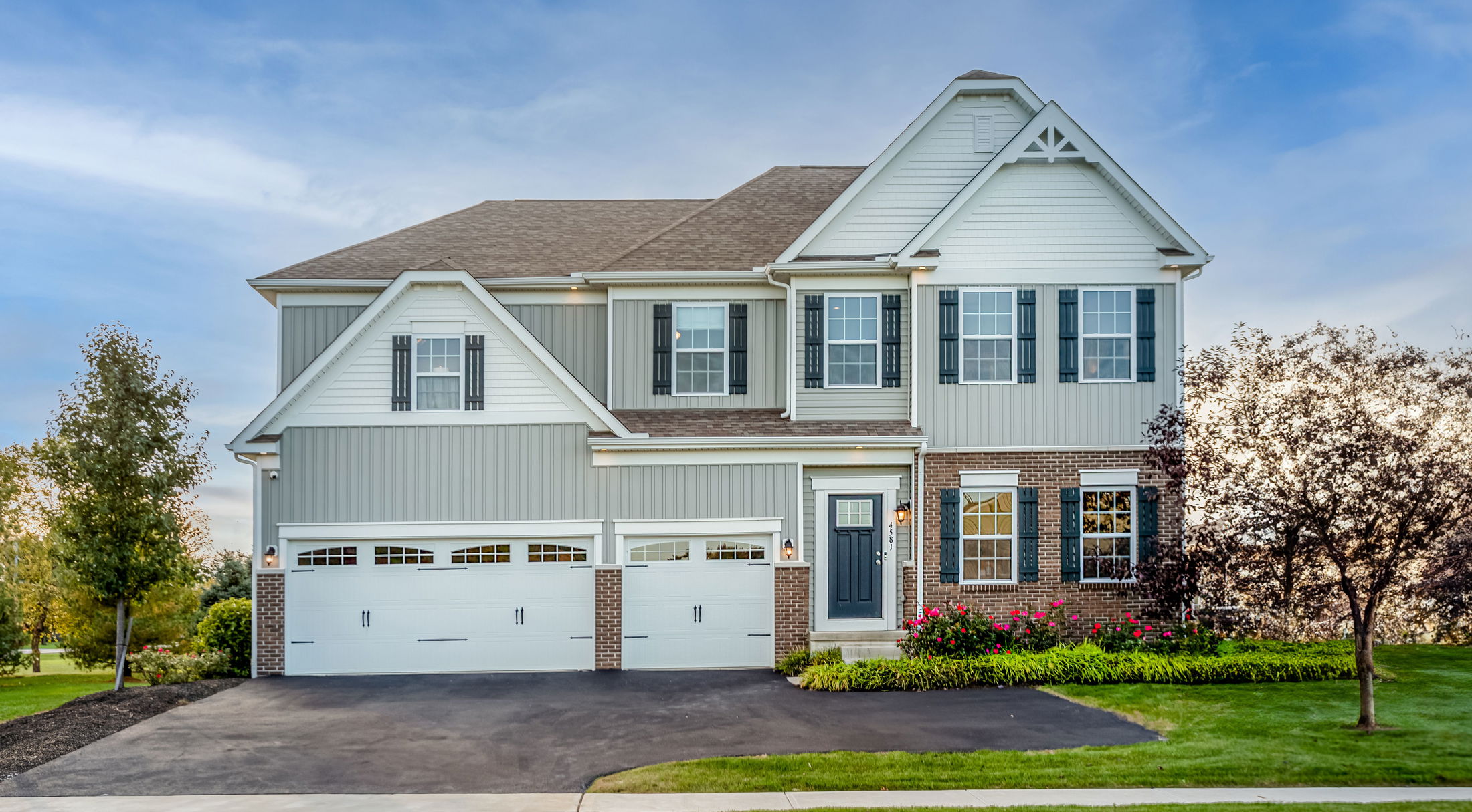 Beautiful two-story suburban home with gray siding, white trim, and a well-maintained front yard.