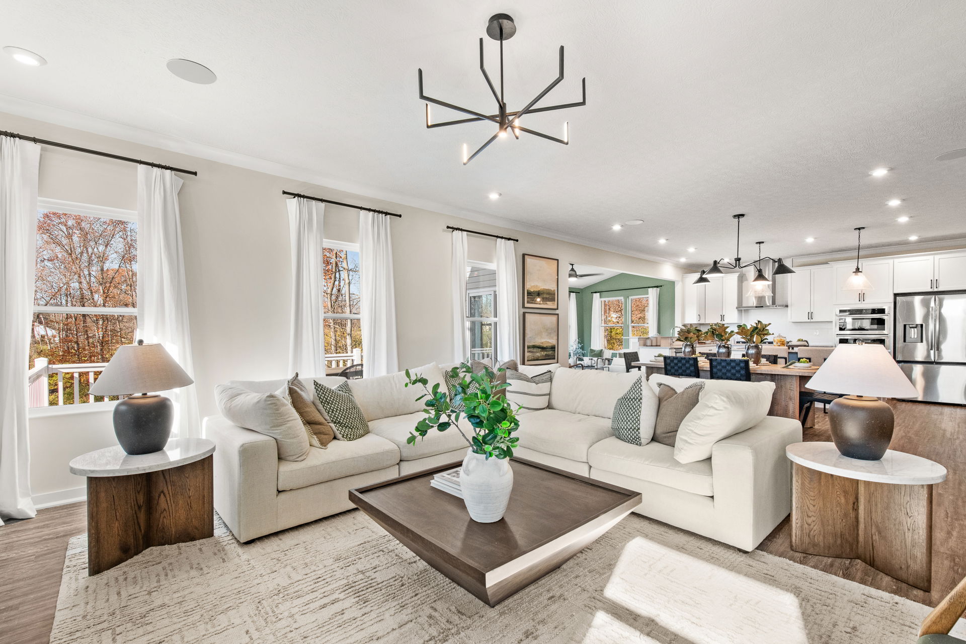 Modern open-concept living room and kitchen with neutral decor and large sectional sofa.