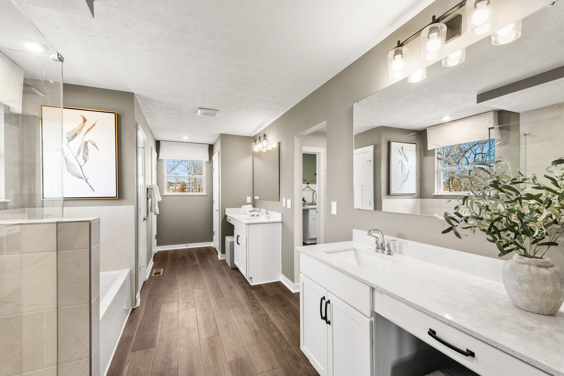 Modern bathroom with elegant fixtures, double vanities, large mirrors, and contemporary decor featuring natural light and wood flooring.