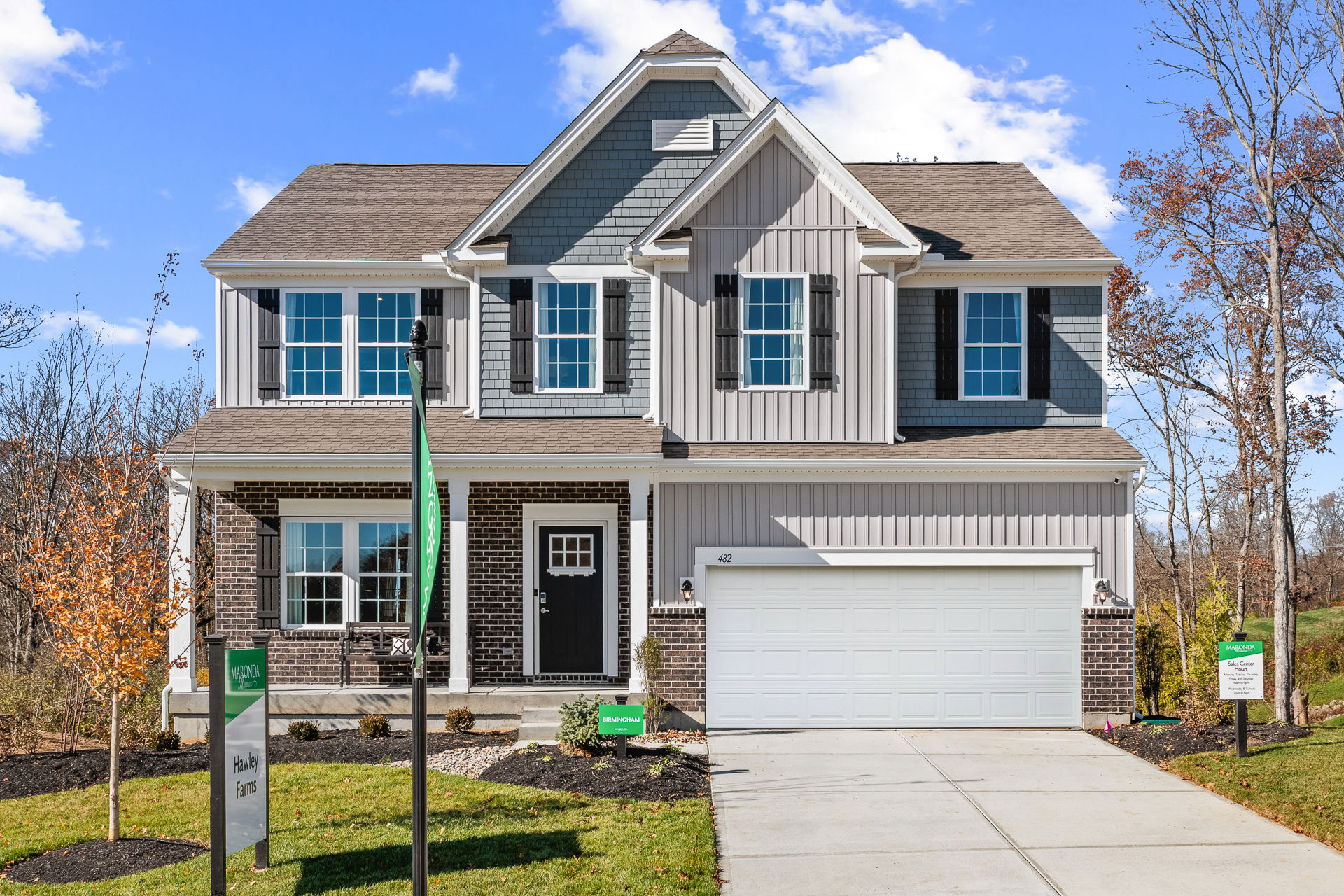 Modern two-story suburban home with brick and siding exterior, double garage, and landscaped front yard set against a clear blue sky.