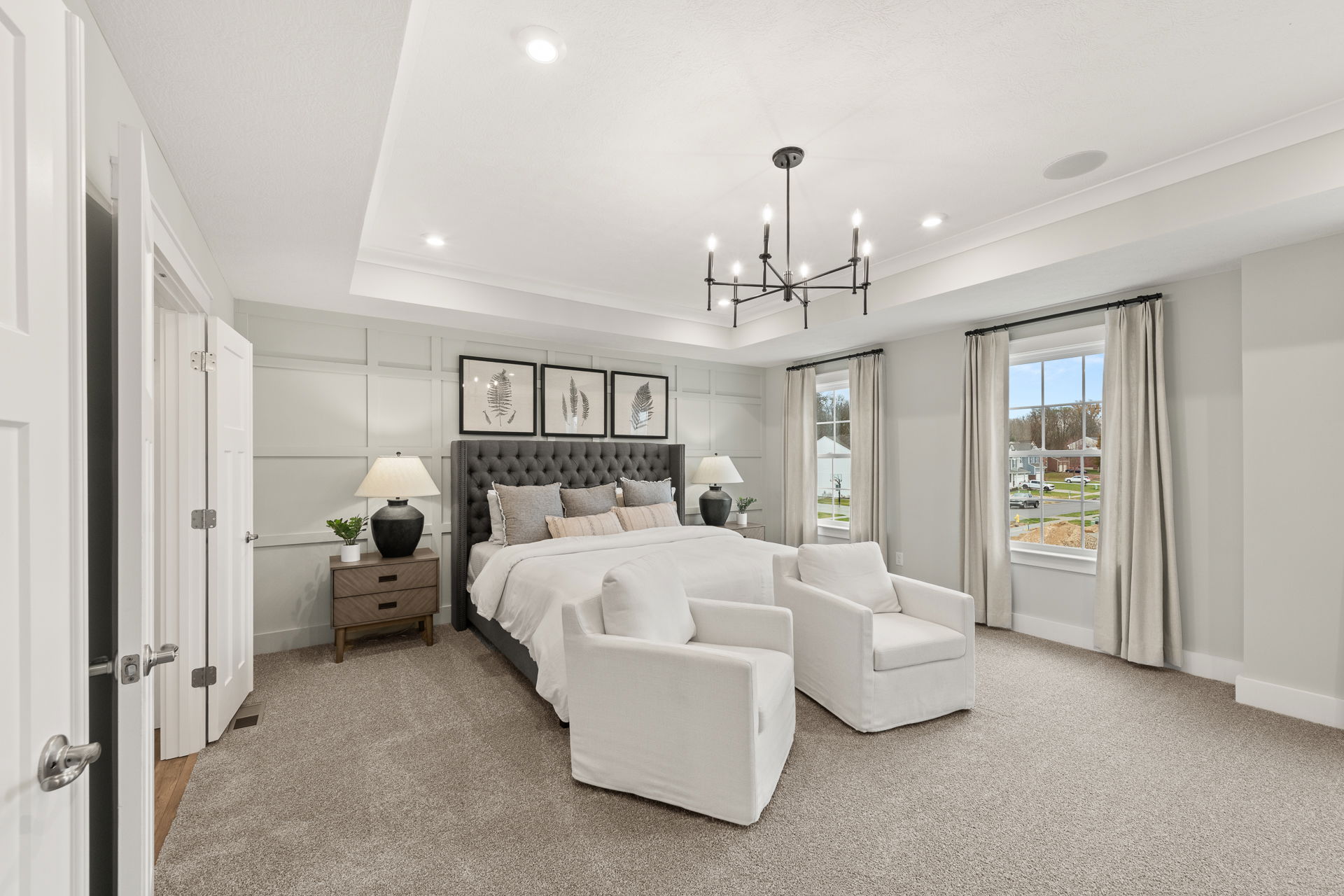 Modern, elegant bedroom with a plush bed, stylish decor, and large windows showcasing a suburban view.