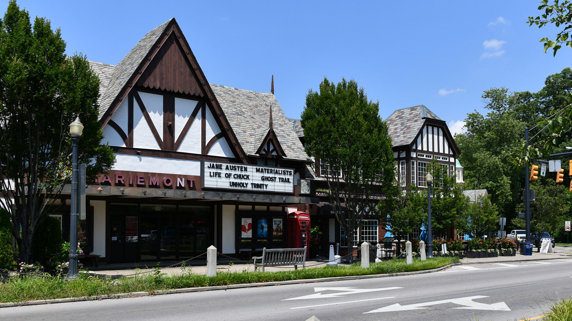 Tudor-style Mariemont Theatre with current movie listings on marquee, surrounded by trees and street view.