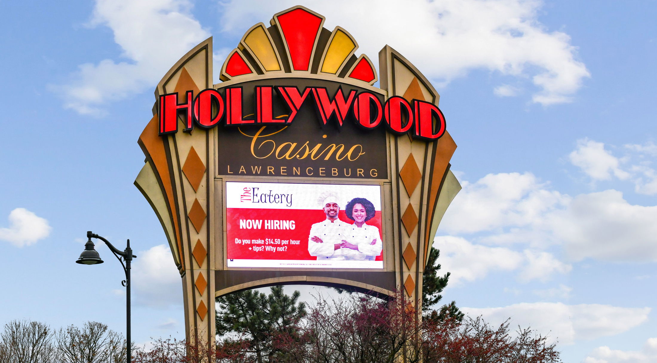 Sign for Hollywood Casino Lawrenceburg featuring a job hiring ad under a blue sky.
