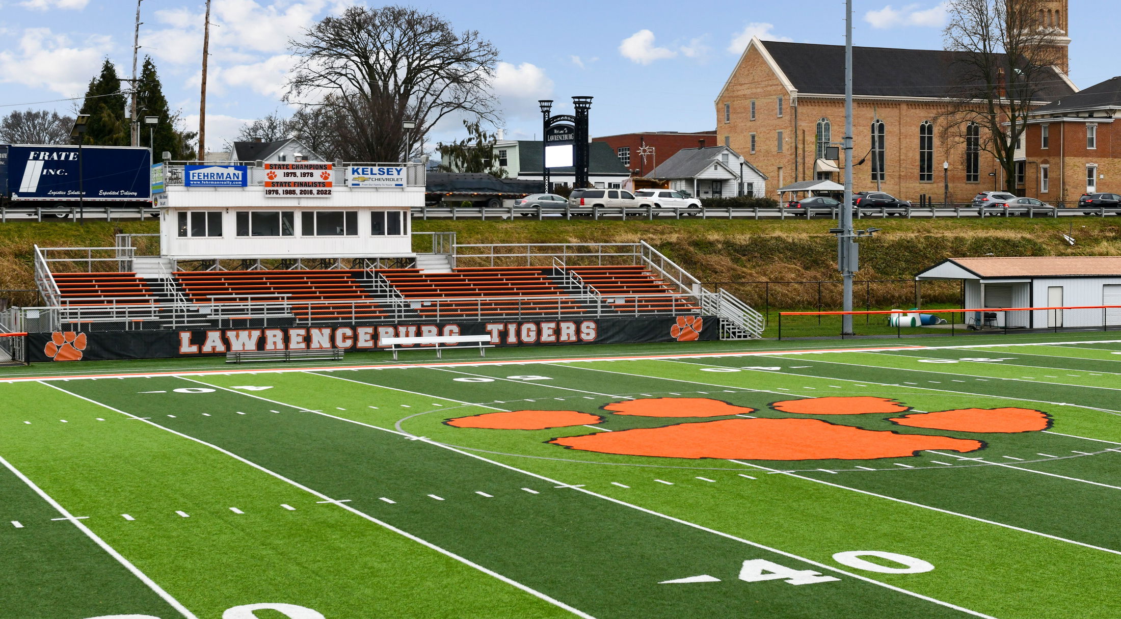 High school football field with a large orange tiger paw logo, bleachers, and \\\\\\\\\\\\\\\\\\\\\\\\\\\\\\\\\\\\\\\\\\\\\\\\\\\\\\\\\\\\\\\\\\\\\\\\\\\\\\\\\\\\\\\\\\\\\\\\\\\\\\\\\\\\\\\\\\\\\\\\\\\\\\\