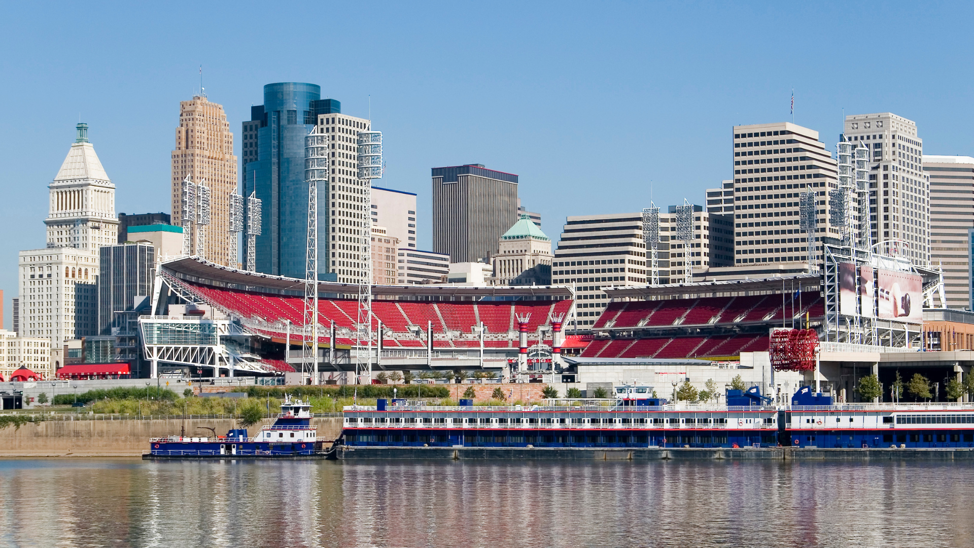 Panoramic view of Cincinnati skyline featuring Great American Ball Park and riverboat on the Ohio River.