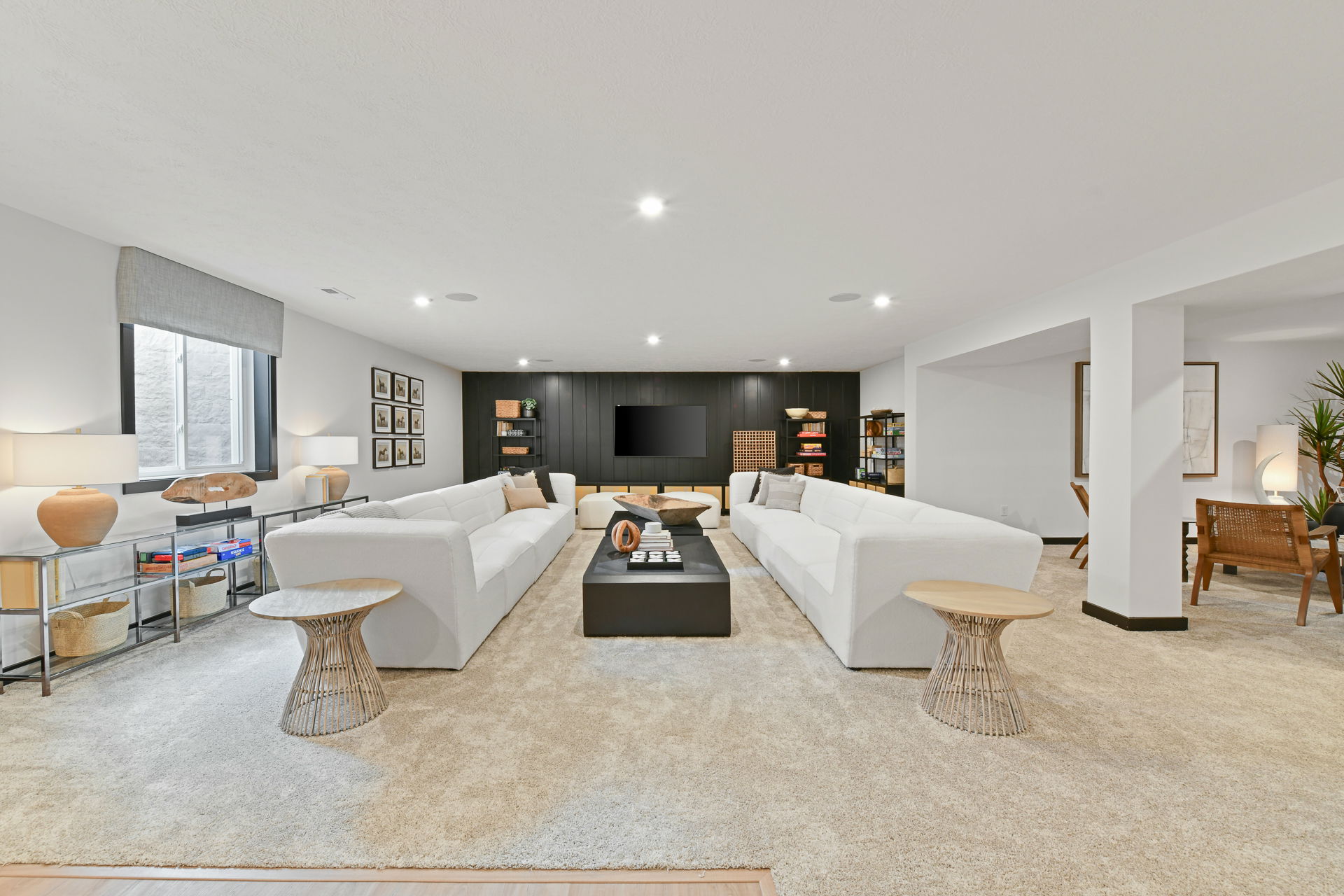 Spacious modern living room with white sectional sofas, a large flat-screen TV, and stylish decor.
