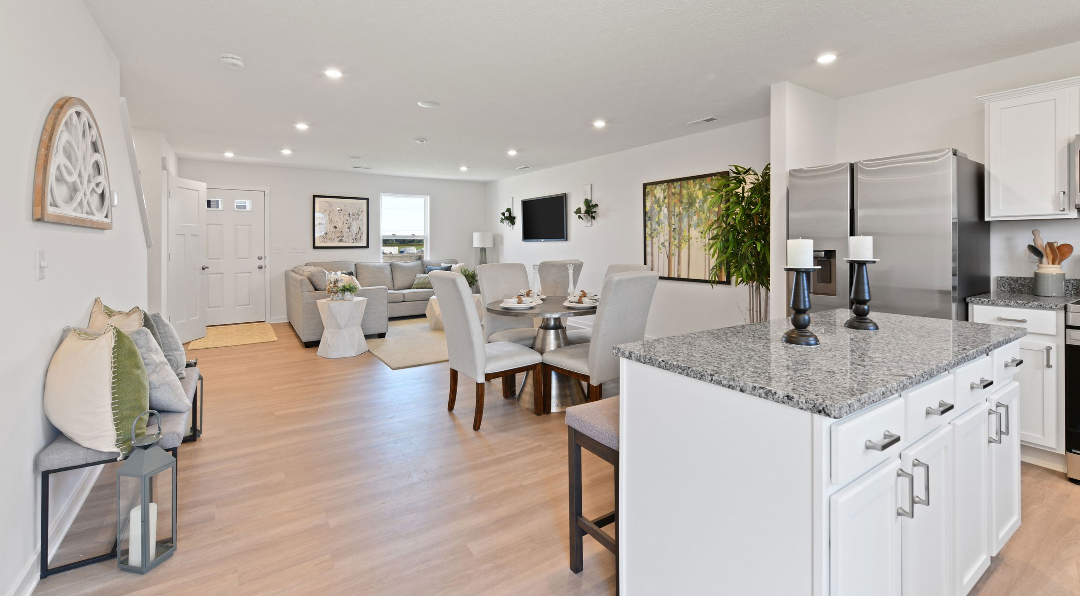 Modern open-concept living space featuring a kitchen with granite countertops, dining area, and stylishly furnished living room with natural lighting.