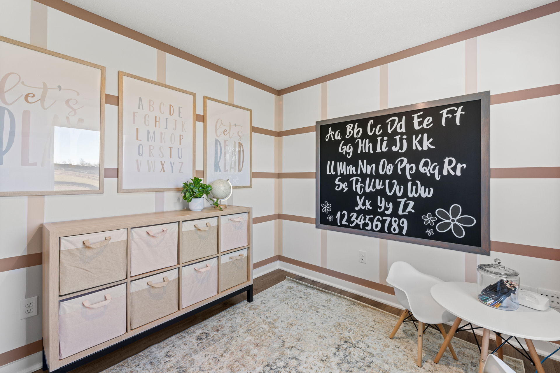 Bright and organized playroom with educational wall decor, storage bins, and a blackboard displaying the alphabet and numbers.