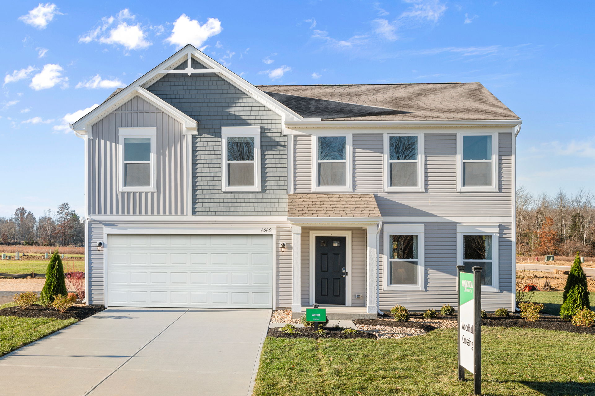 Modern two-story suburban house with grey siding, a double garage, and a well-maintained lawn.