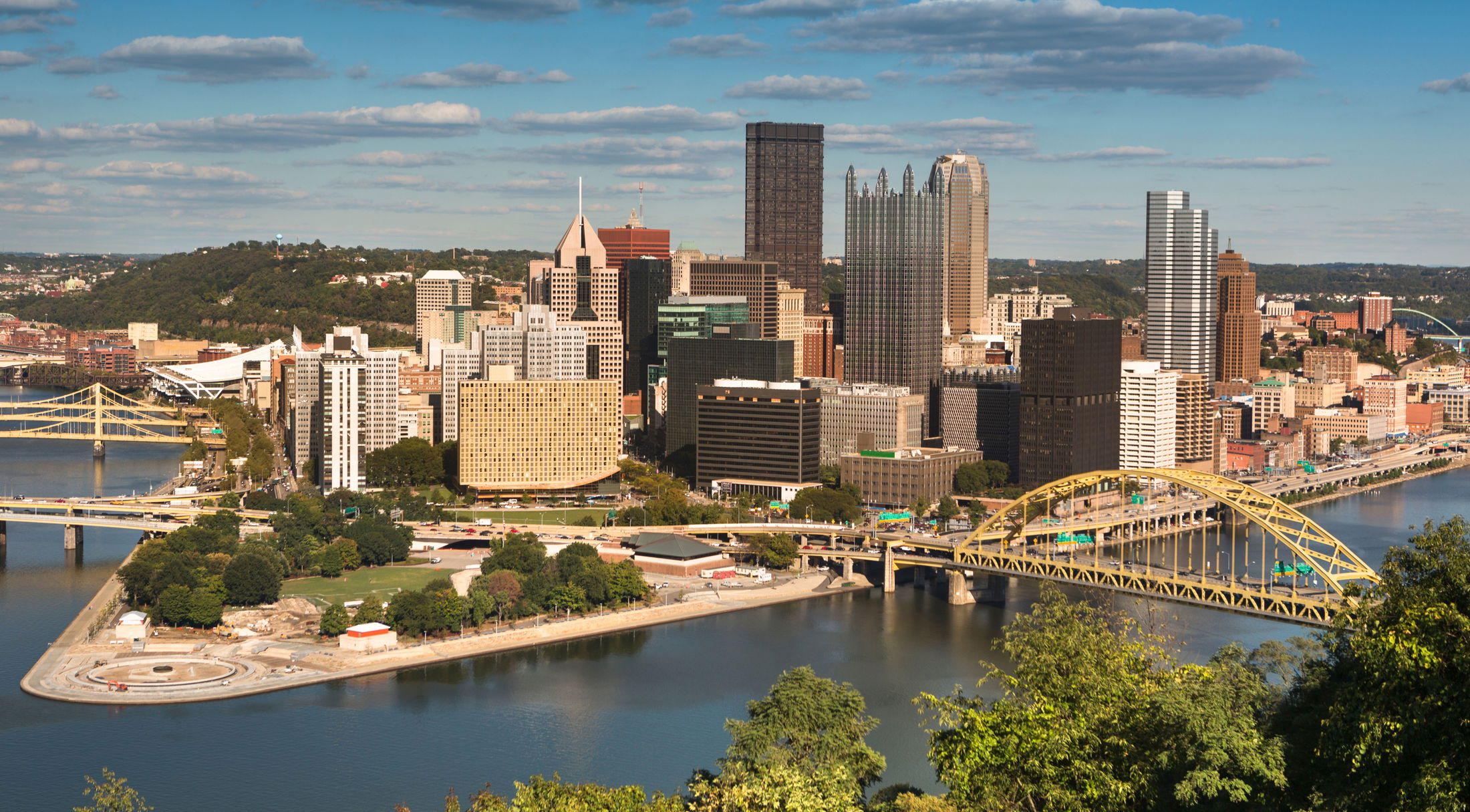 Skyline of Pittsburgh with iconic bridges over the river on a sunny day.