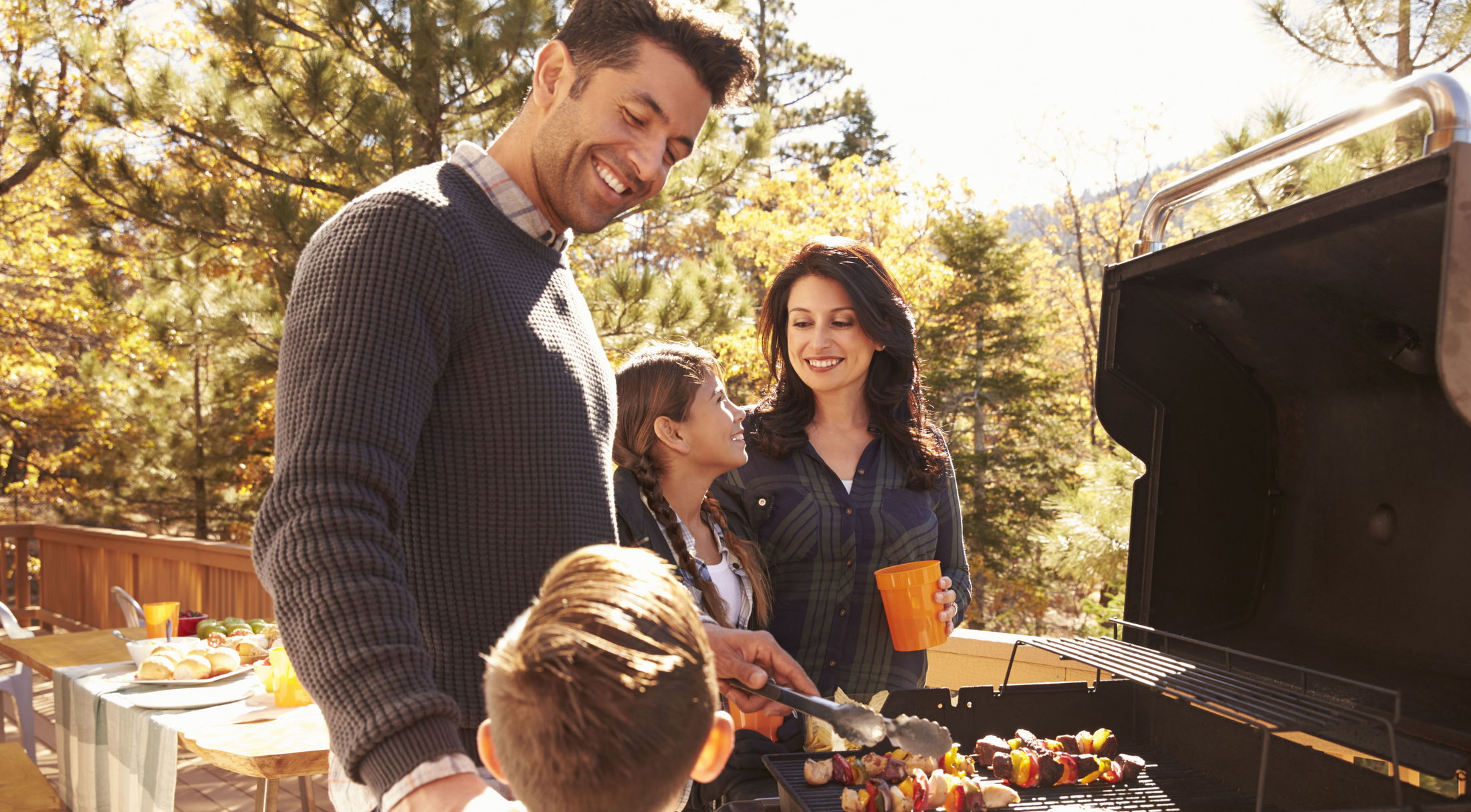 A family enjoying an outdoor barbecue together on a sunny day in the backyard.