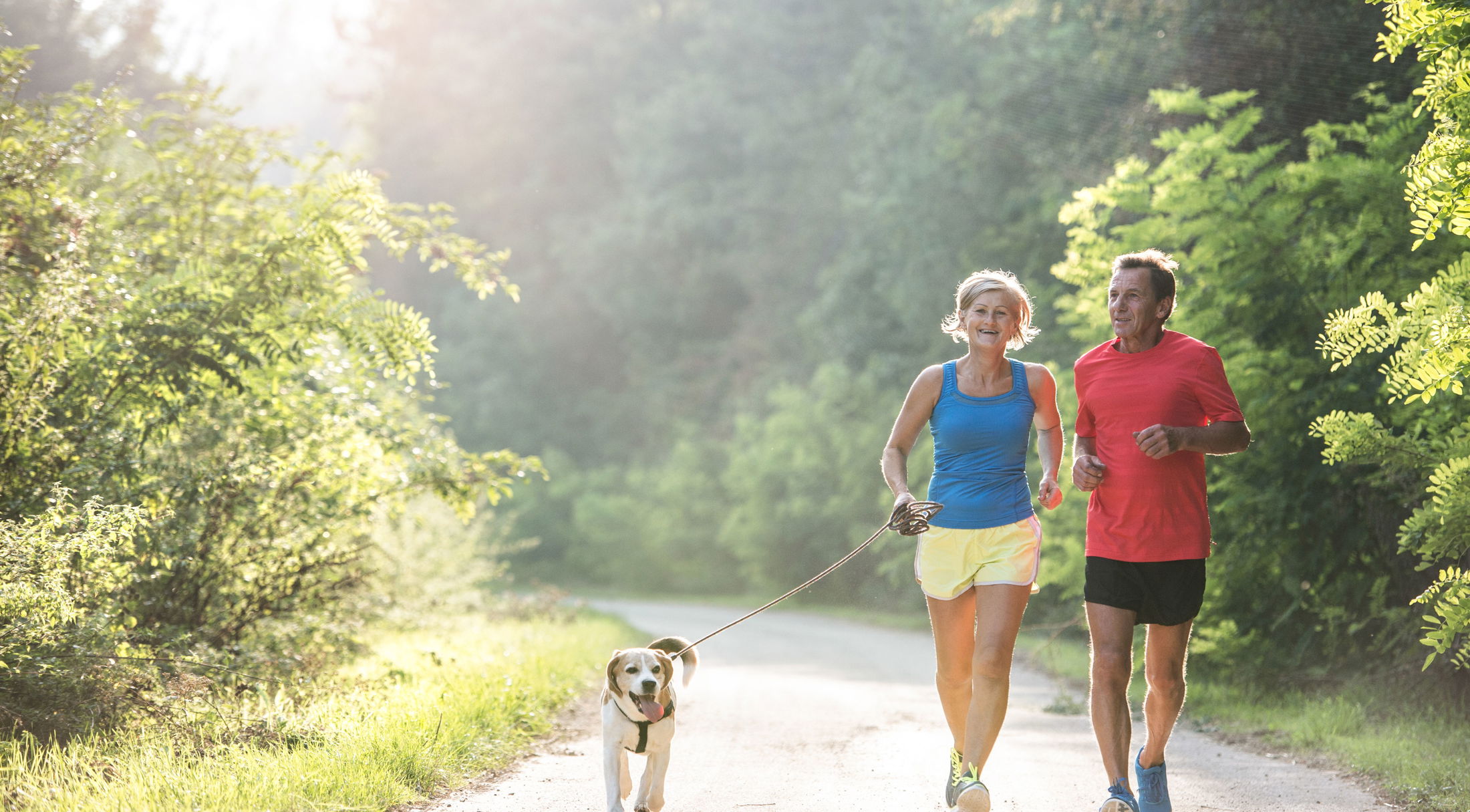 a couple running on a trail with their dog