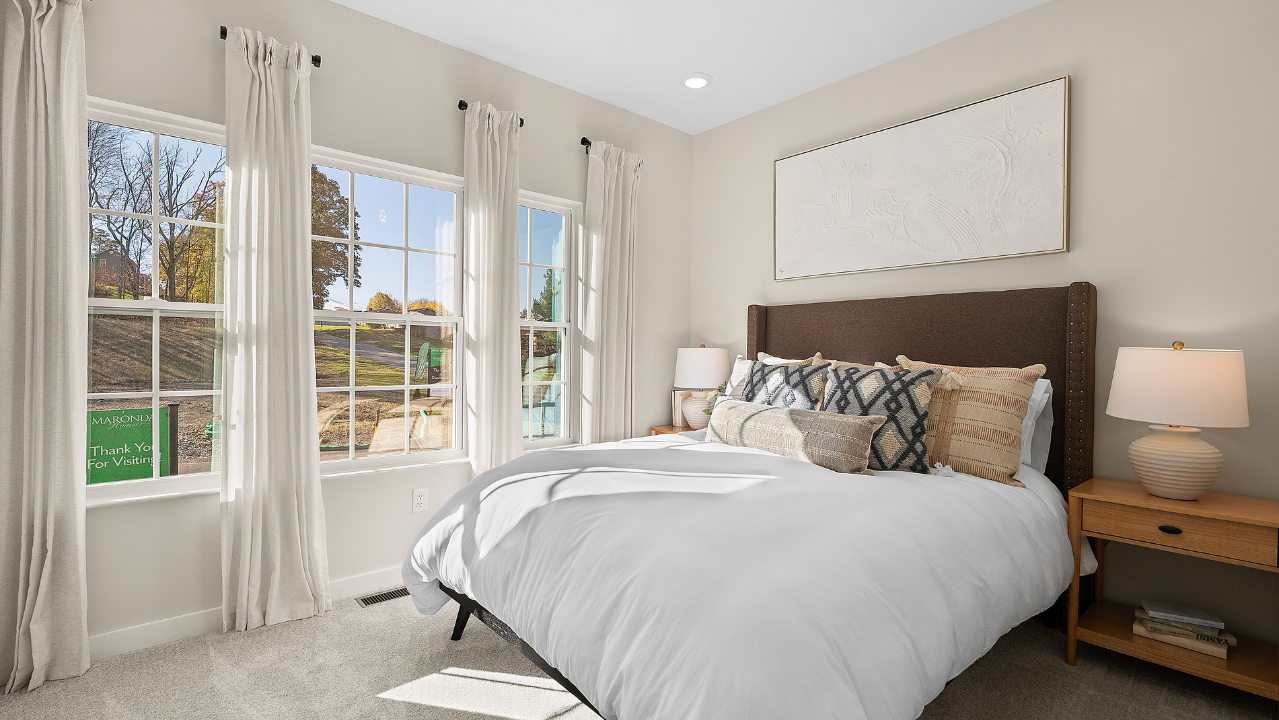 Bright and cozy bedroom interior with a large window, stylish bed, and decorative pillows, ideal for natural light lovers.