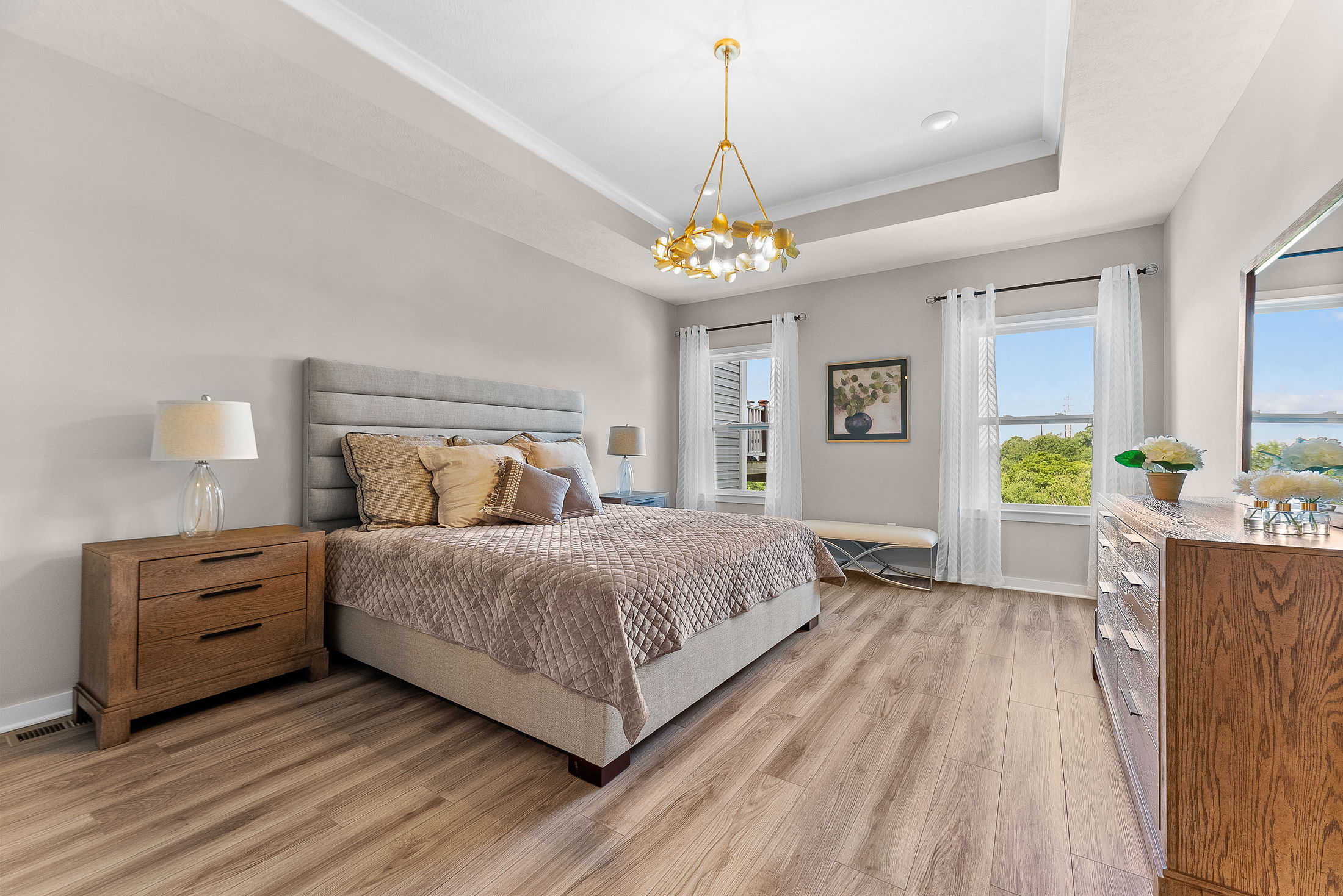 Luxurious modern bedroom with stylish decor, wooden flooring, and large windows offering natural light and scenic views.