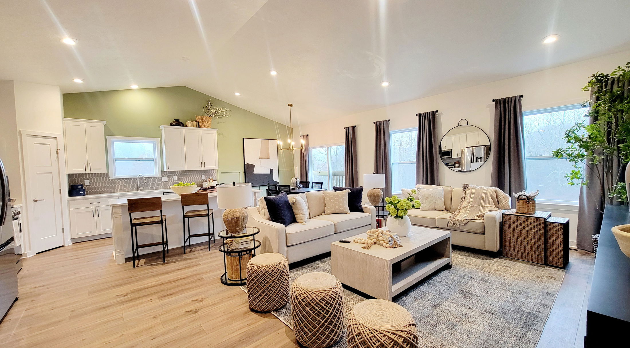 Modern open-concept living room and kitchen with stylish decor, featuring neutral tones, natural light, and elegant furnishings.