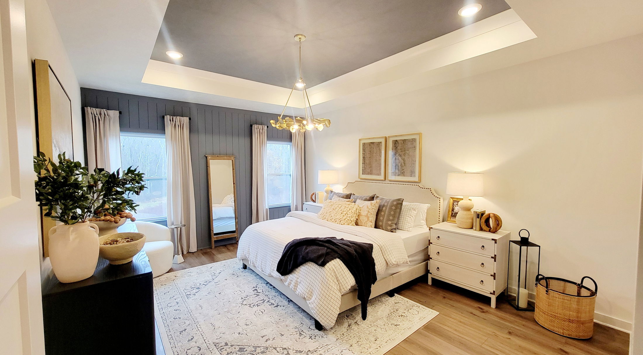 Elegant master bedroom with modern lighting, cozy bedding, and stylish decor accents on a wooden floor and area rug.