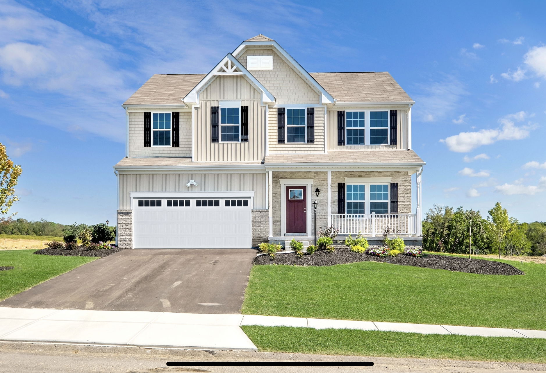 Two-story suburban home with a welcoming porch, landscaped yard, and attached garage on a sunny day.