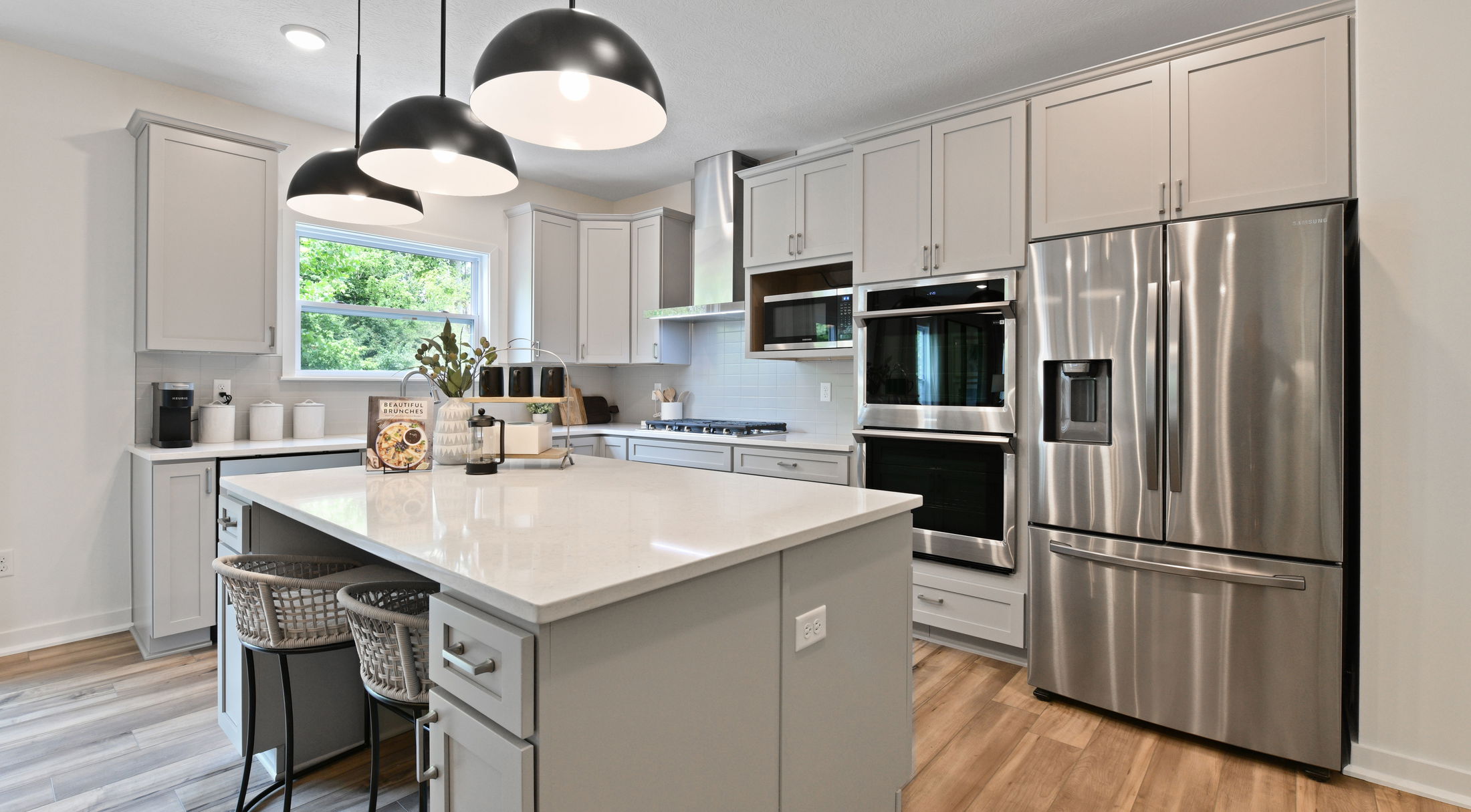 Modern kitchen with stainless steel appliances, large island, white cabinets, and pendant lighting.