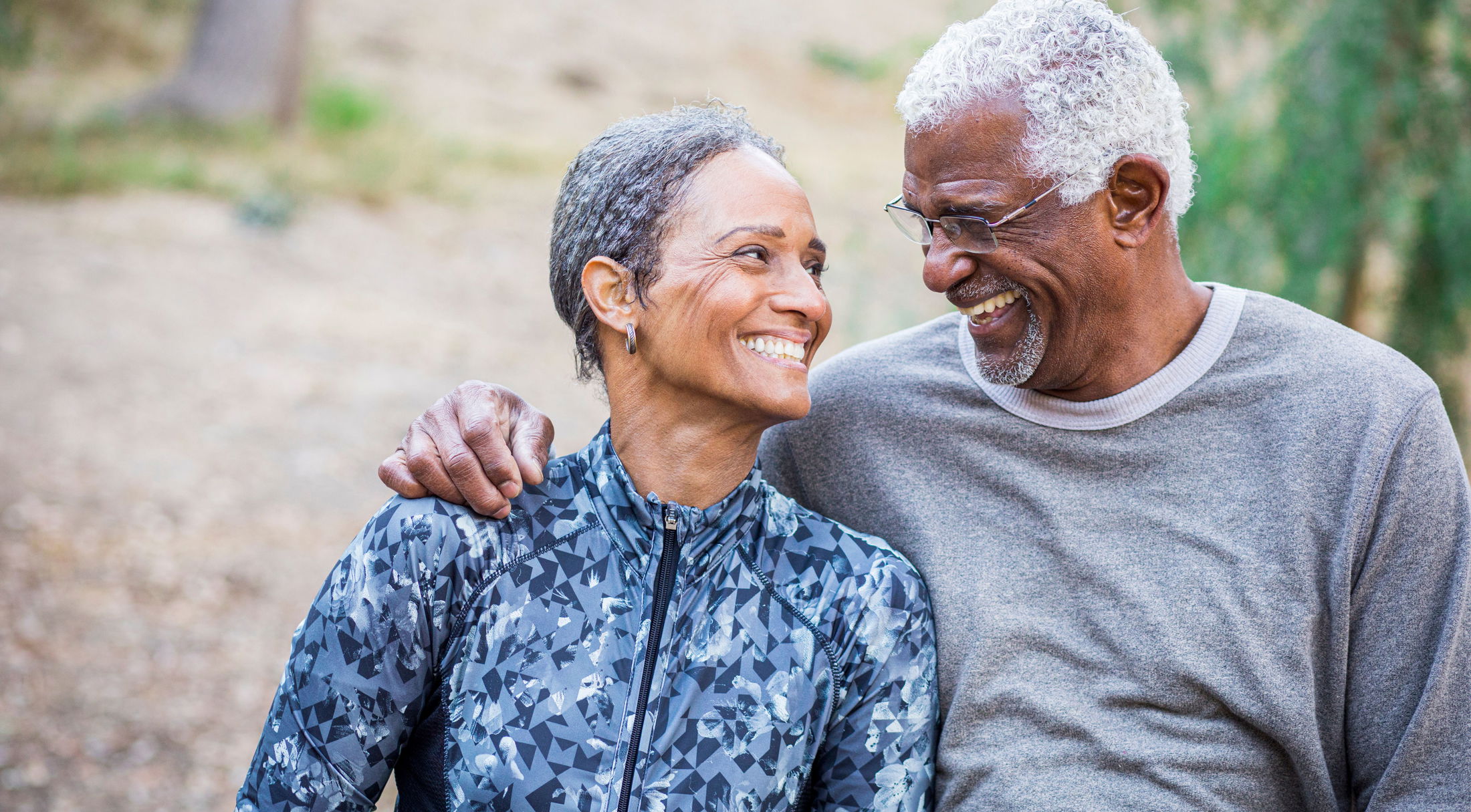 Smiling elderly couple enjoying an outdoor walk together, showcasing happiness and companionship in nature.
