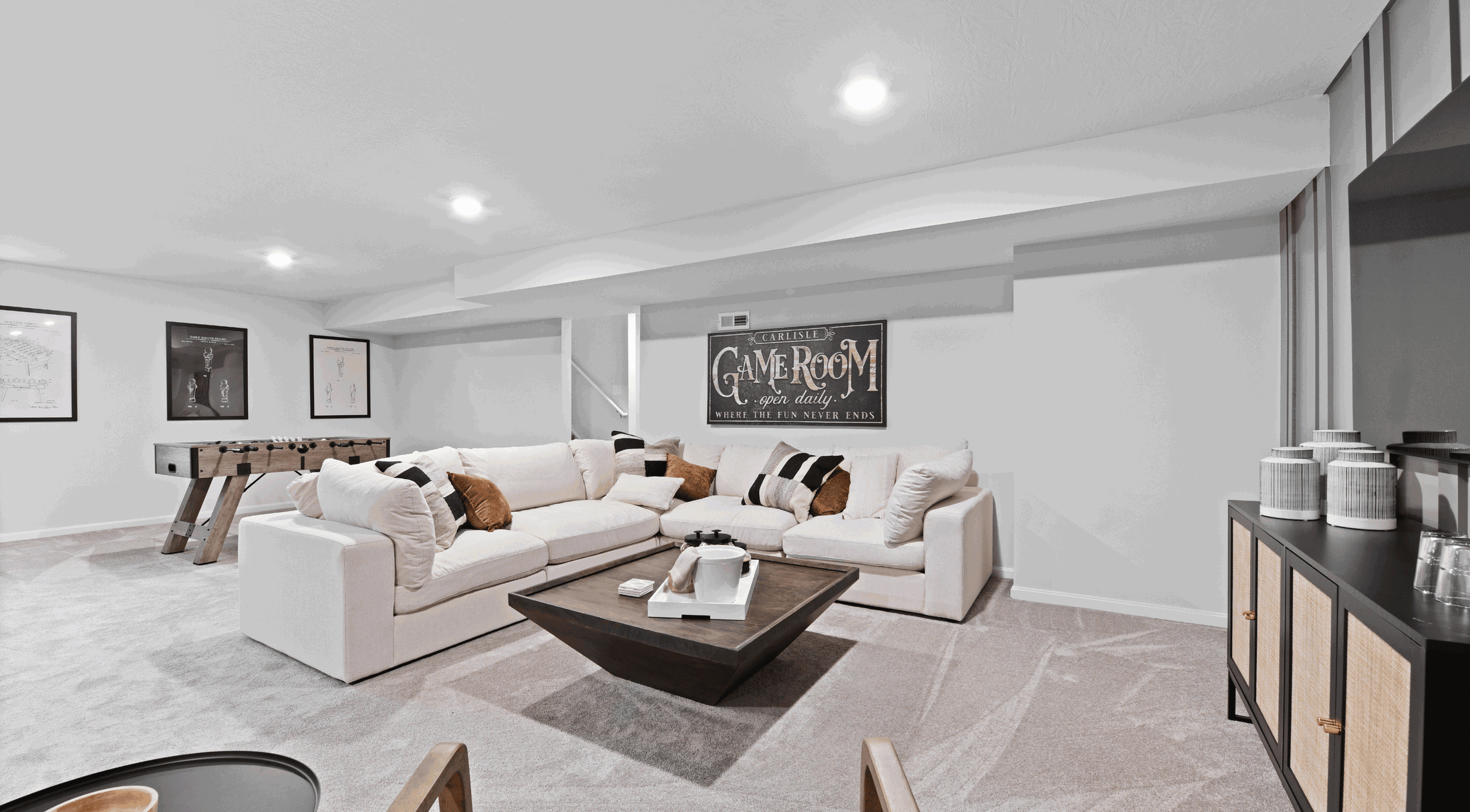 Modern basement game room with cozy sectional sofa, foosball table, and stylish decor.