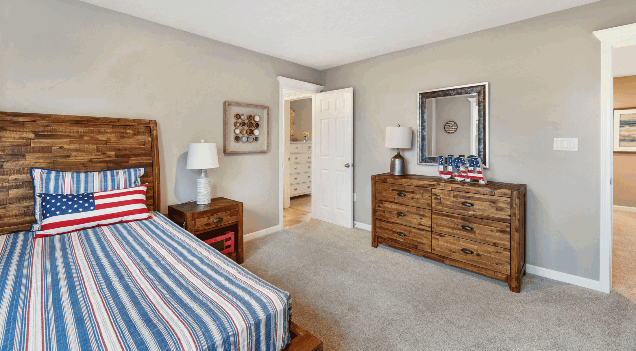 Cozy bedroom with a rustic wooden bed and dresser, featuring patriotic American flag-themed bedding and decor.