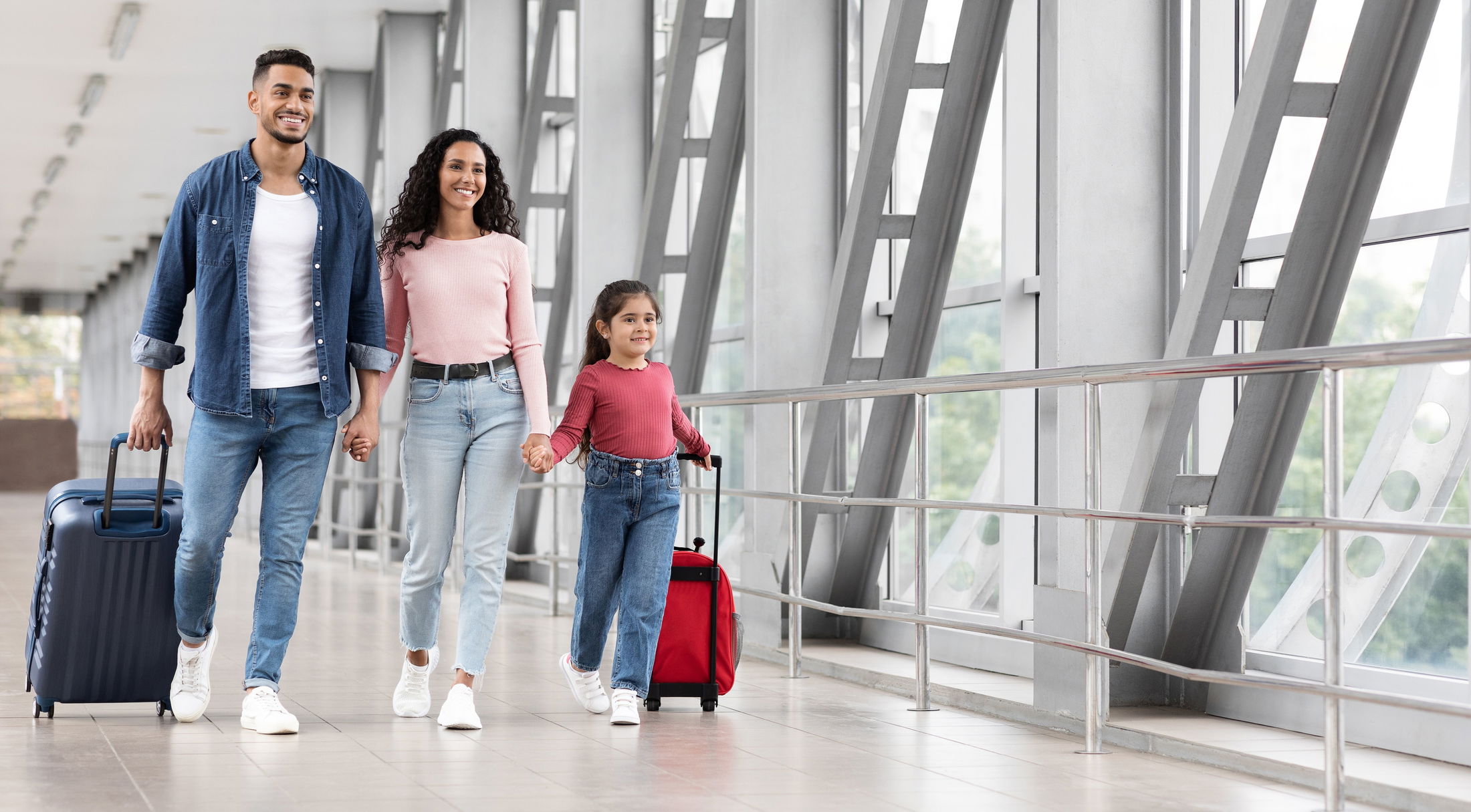 a family of three walking through the pittsburgh international airport