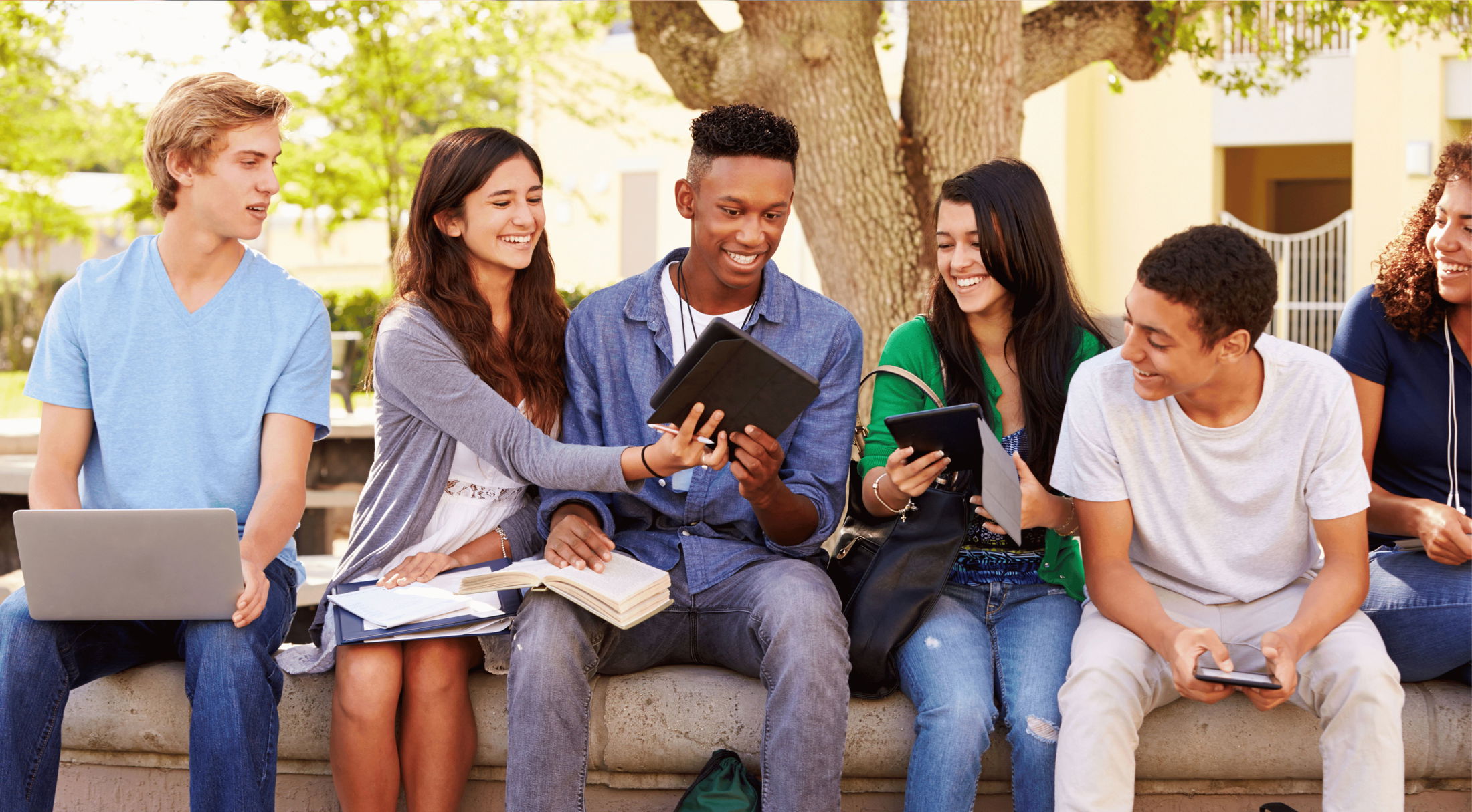 five friends looking at their electronics outside at rmu
