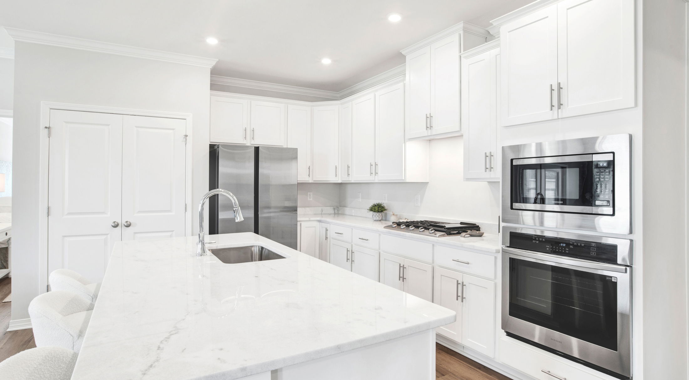Sleek modern kitchen with white cabinetry, stainless steel appliances, and a central island featuring a polished countertop.