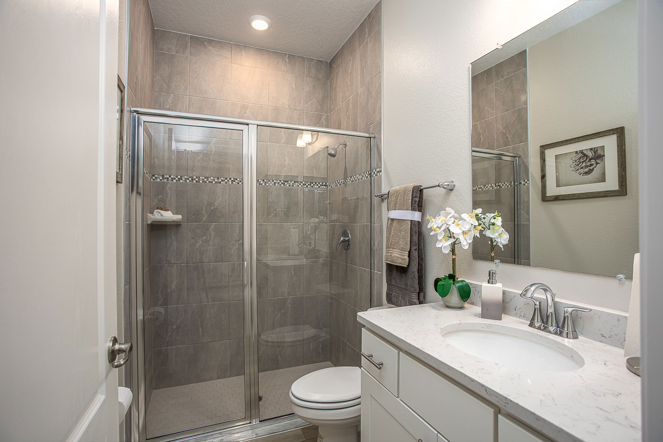 Modern bathroom with glass-enclosed shower, marble countertop, and elegant decor.
