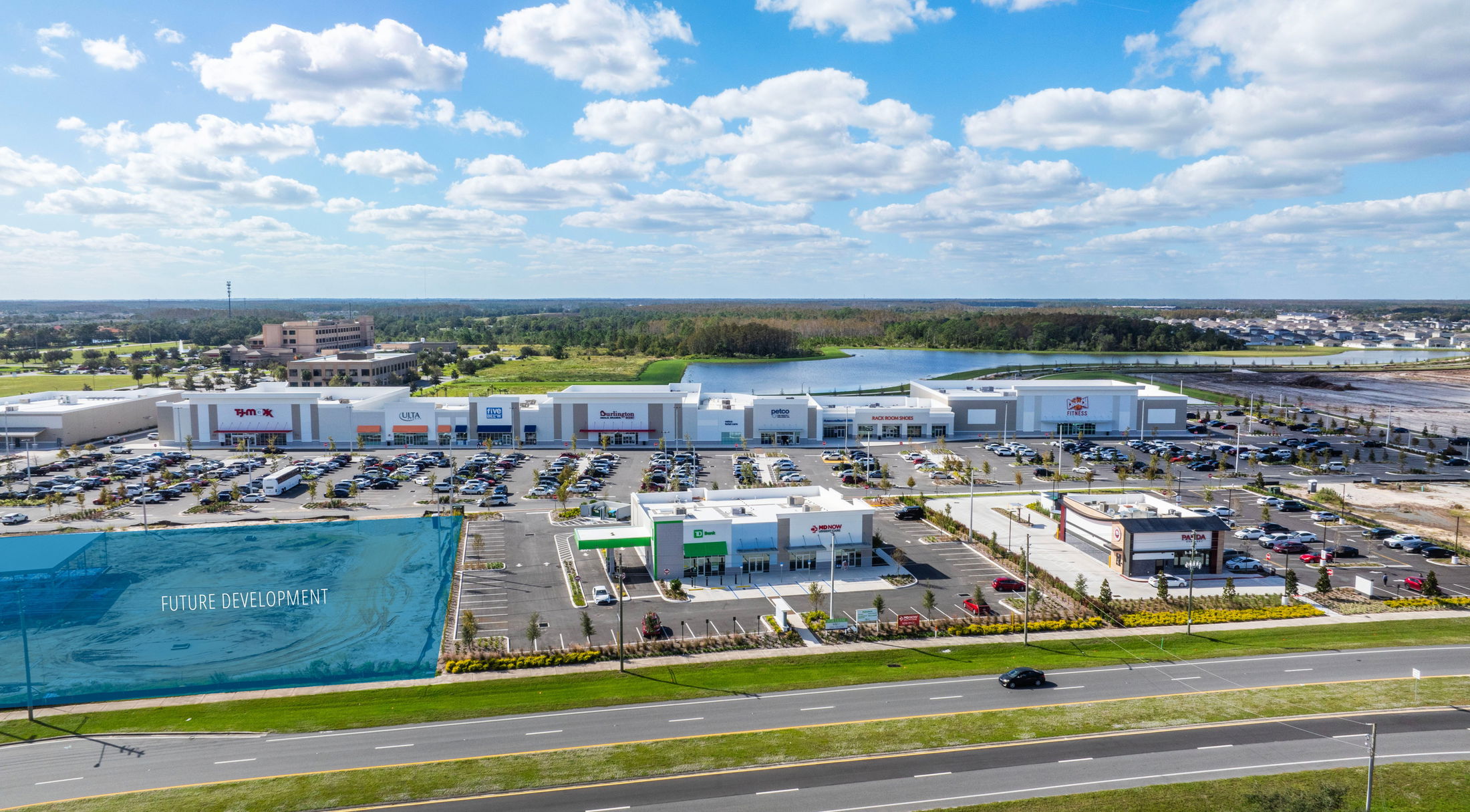 Aerial view of a busy shopping center with popular retail stores and a labeled future development area under a clear blue sky.