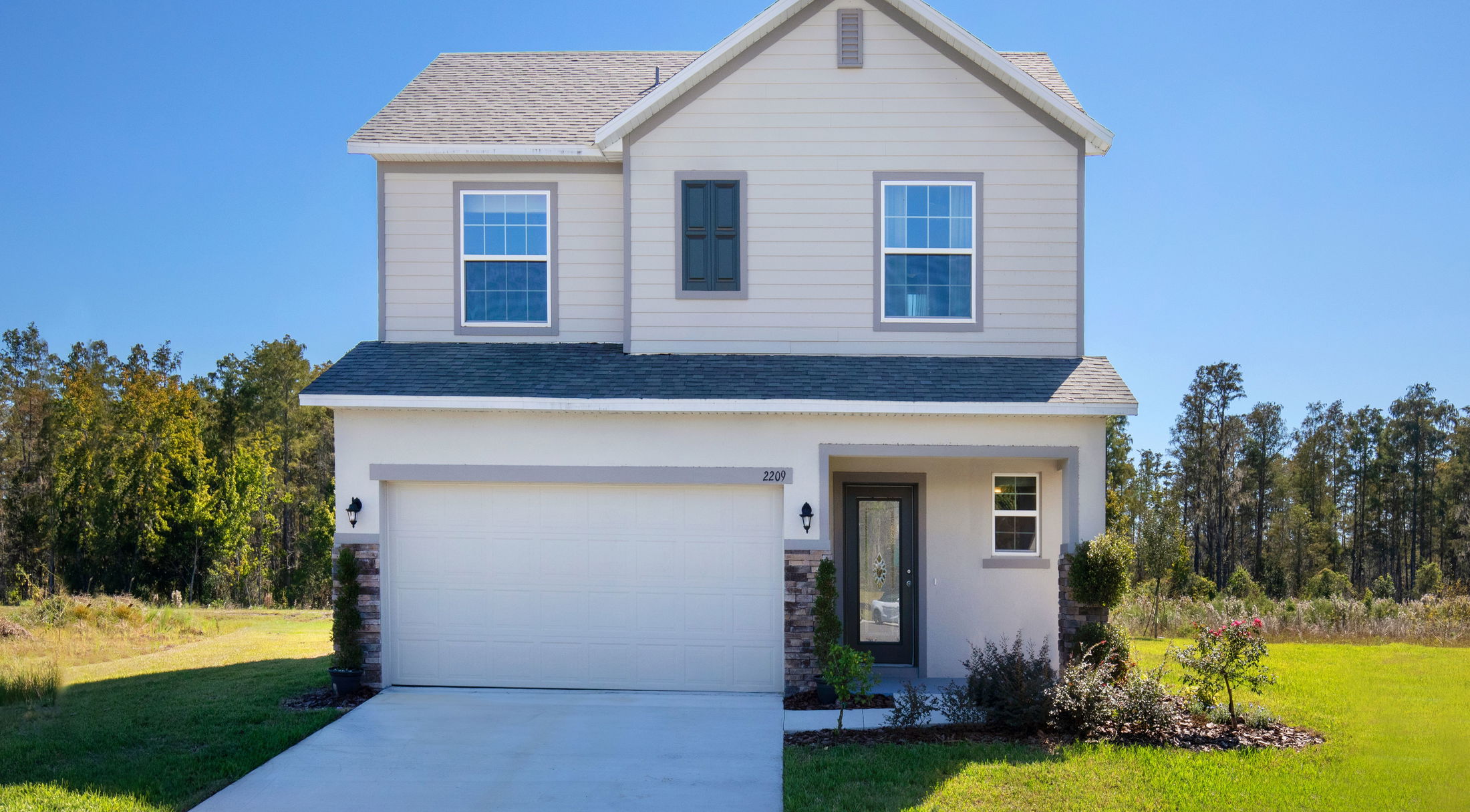 Front view of a modern two-story suburban house with a well-manicured lawn and attached garage.