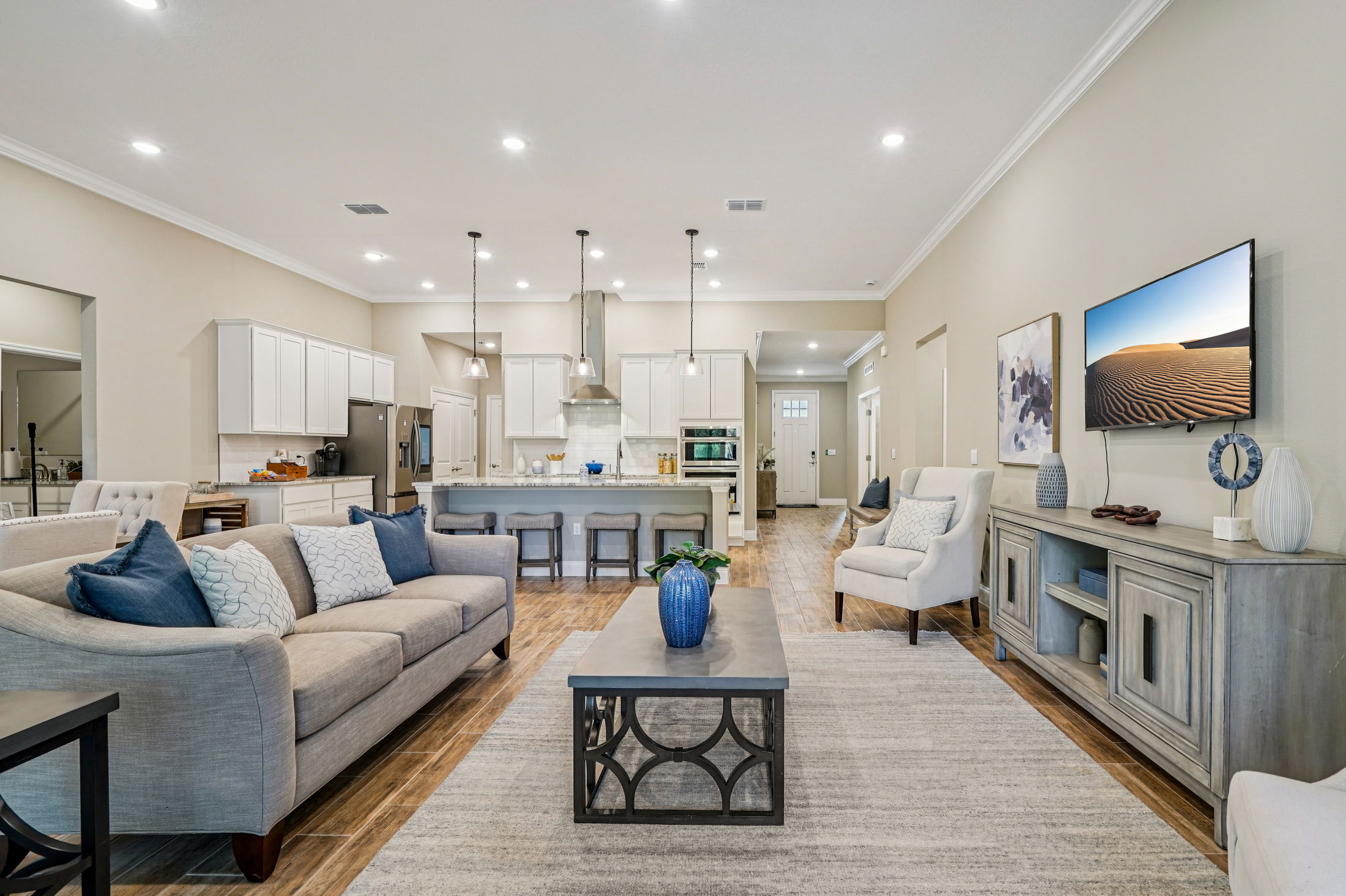 Modern living room interior featuring a gray sofa with blue accents, a coffee table, and an open-concept kitchen in a contemporary home.