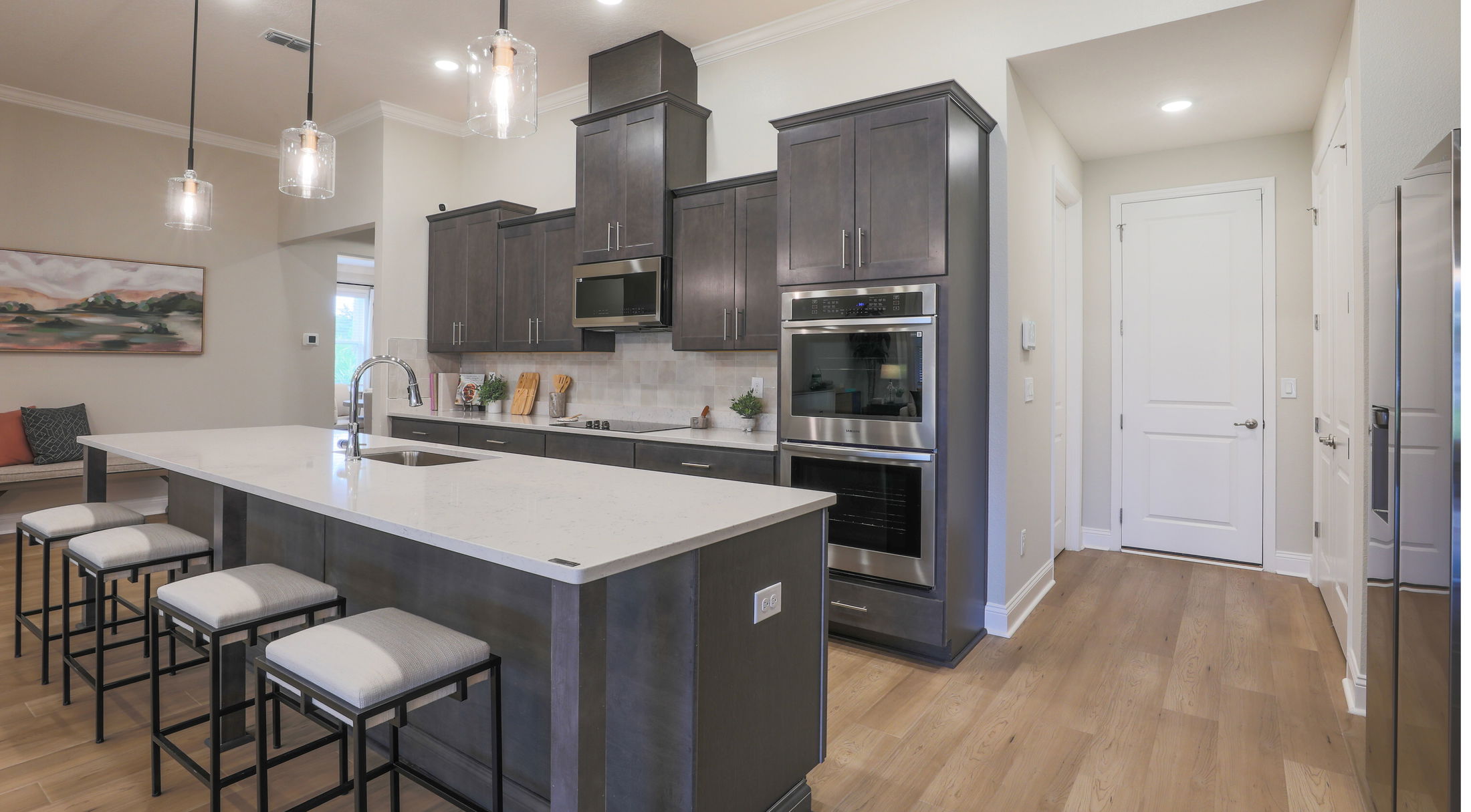 Modern kitchen with dark cabinets, stainless steel appliances, and a large white island with seating.