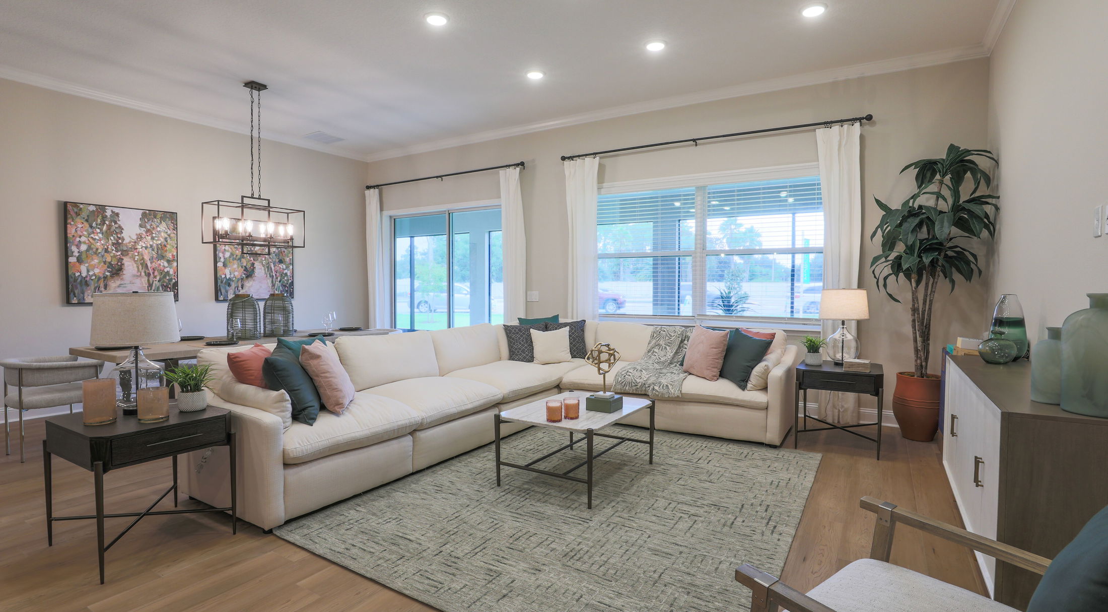 Spacious modern living room with white sectional sofa, decorative pillows, stylish artwork, and panoramic window view.