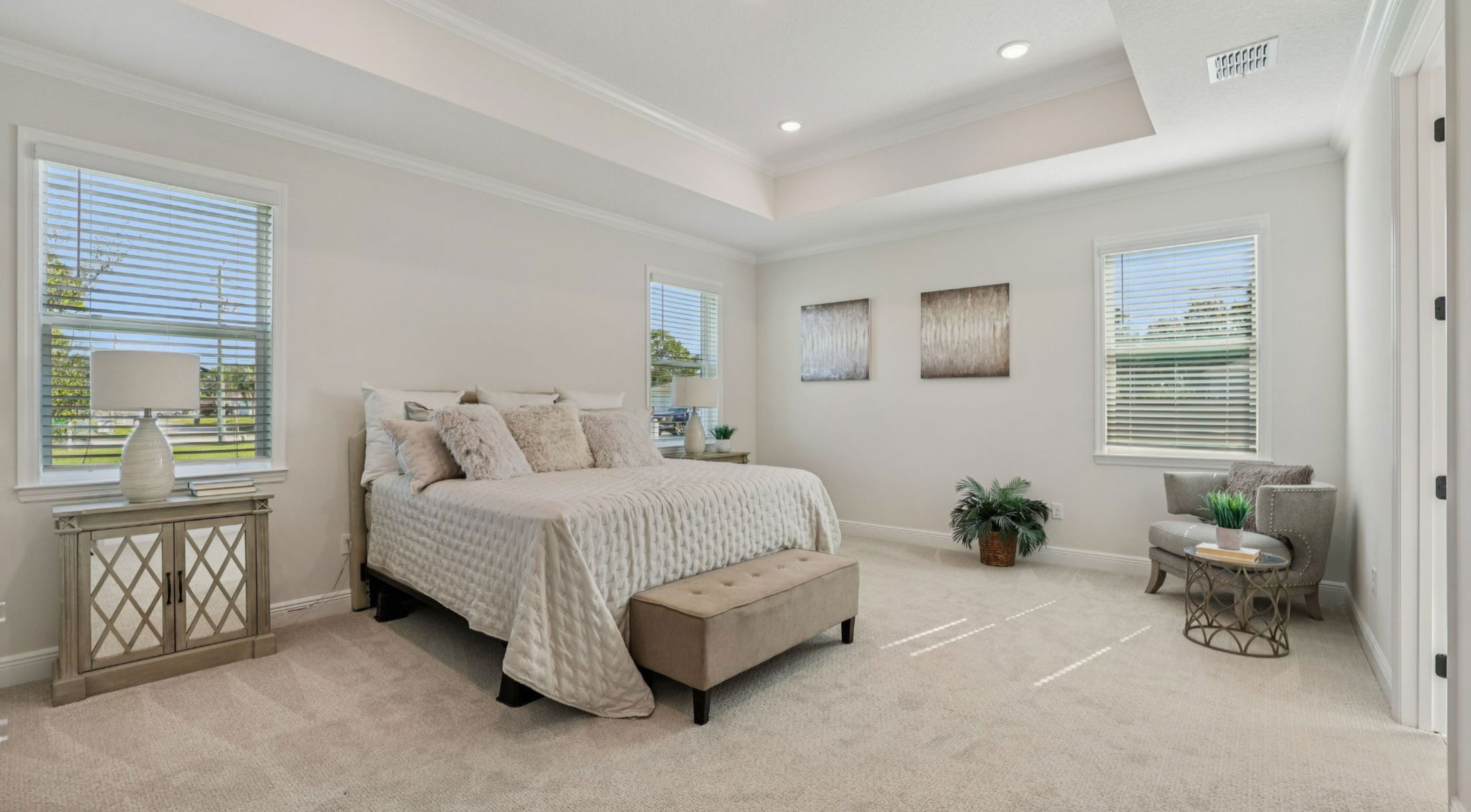 Modern and stylish bedroom featuring a comfortable bed, plush decor, and natural light from large windows.