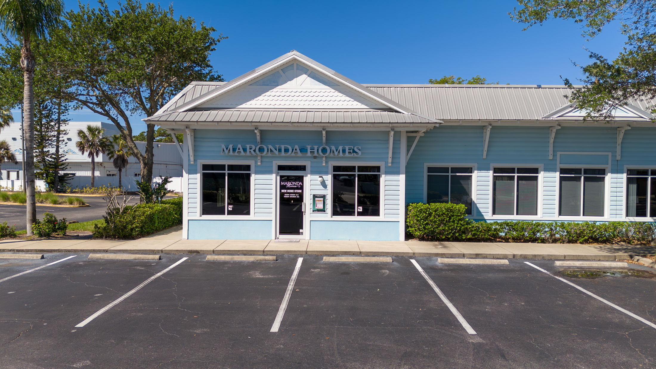 Front view of a Maronda Homes sales office building with a light blue exterior and an empty parking lot.