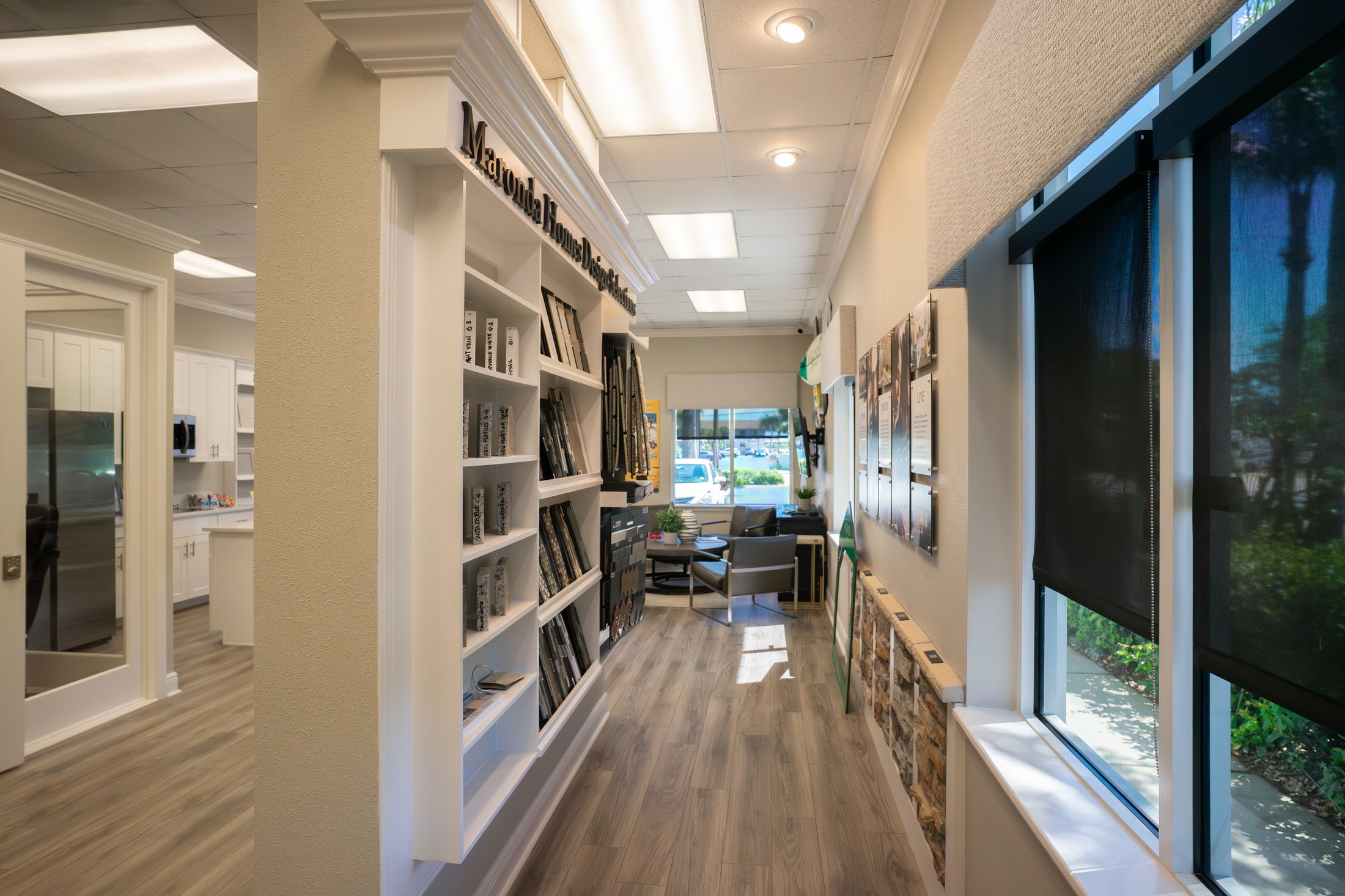 Modern interior hallway in a design studio with wood flooring, large windows, and an organized display shelf.