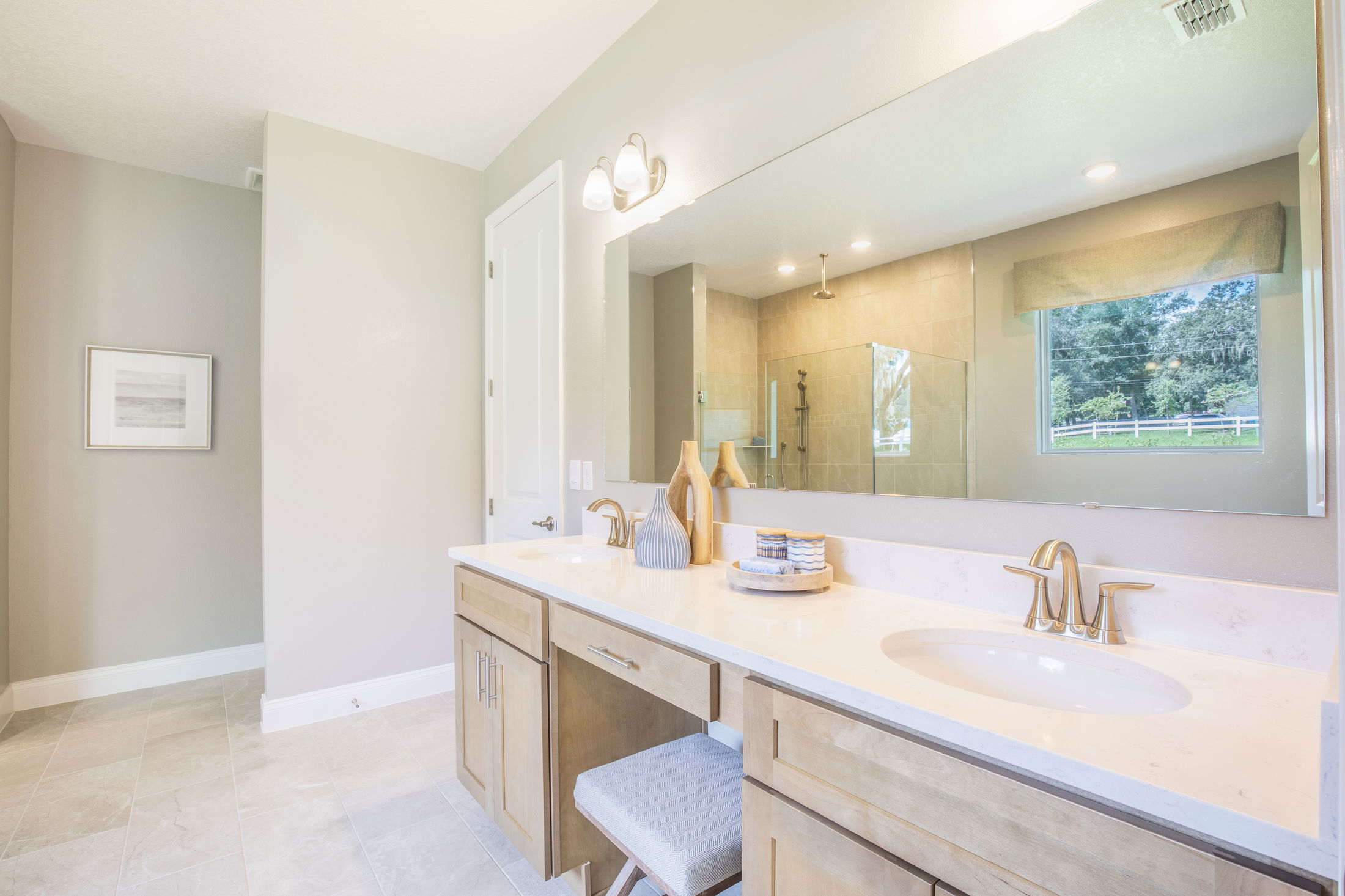 Modern bathroom with light wood cabinets, a large mirror, and a glass shower enclosure.