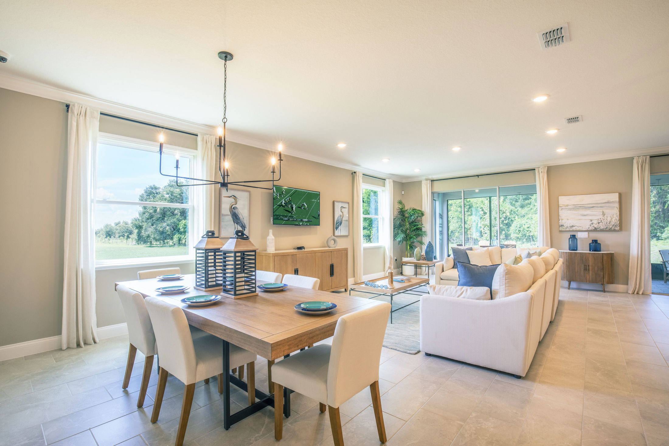 Modern open-concept living room with elegant dining area, neutral decor, large windows, and tasteful furnishings.