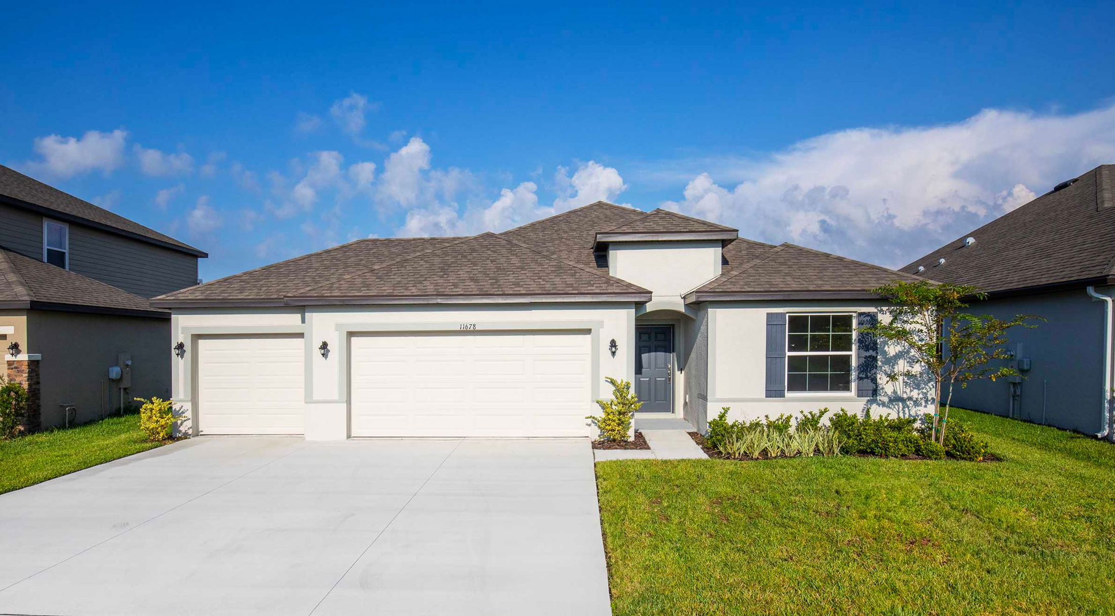 Modern single-story home with two-car garage, manicured lawn, and clear blue sky background.