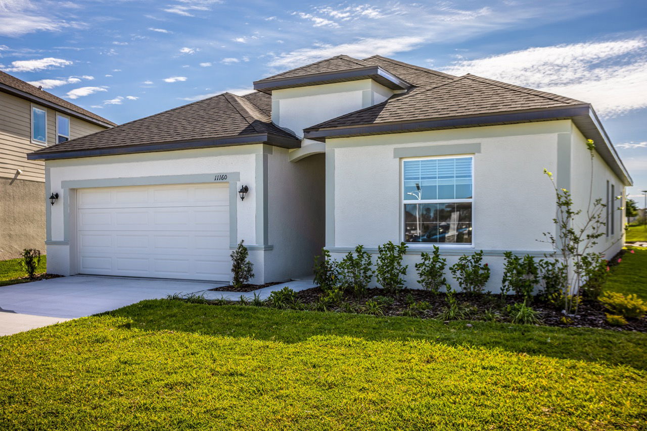 Modern single-story home with white exterior, two-car garage, and well-maintained landscaping under a clear blue sky.