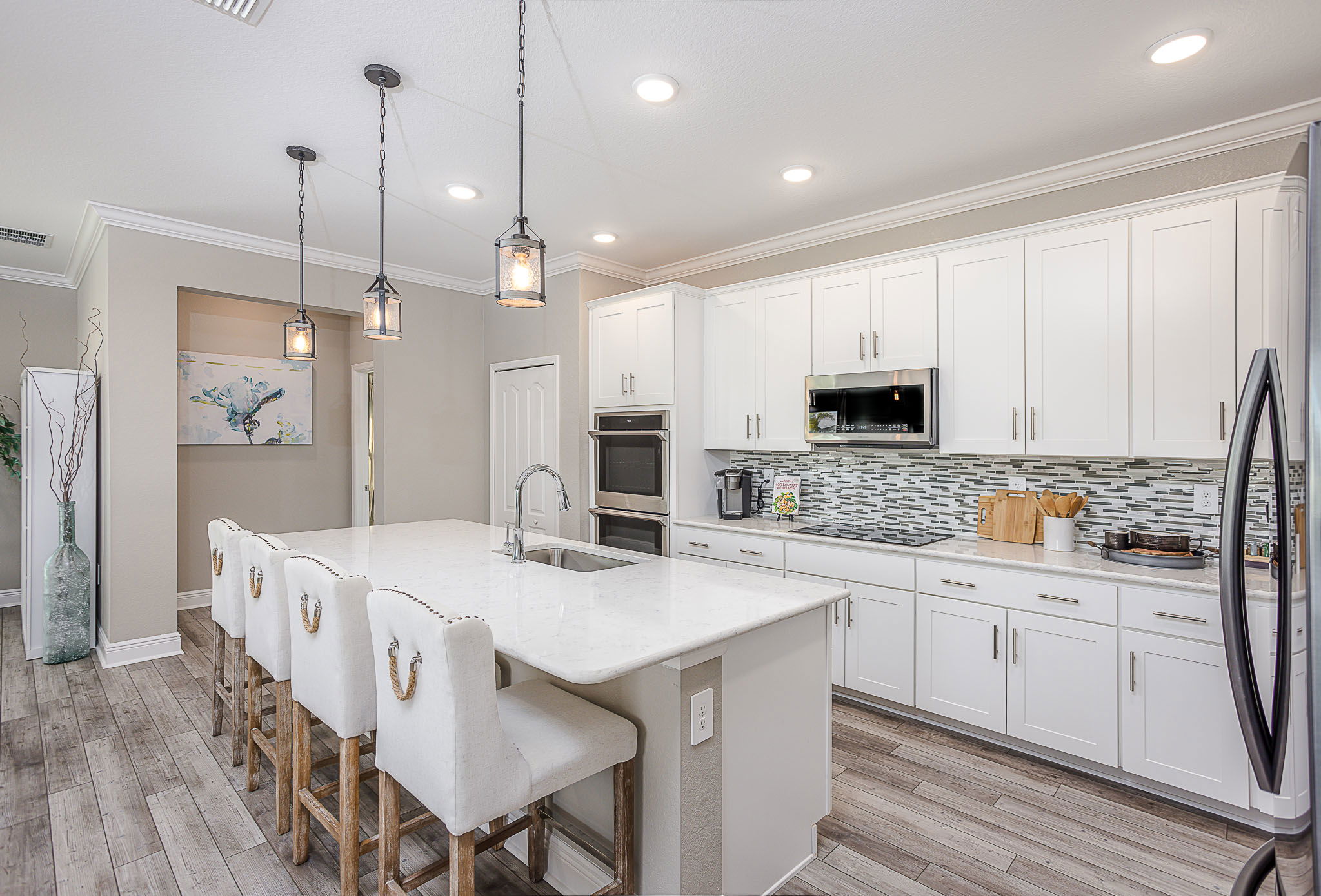 Modern kitchen with white cabinetry, a marble island, pendant lighting, and stainless steel appliances.