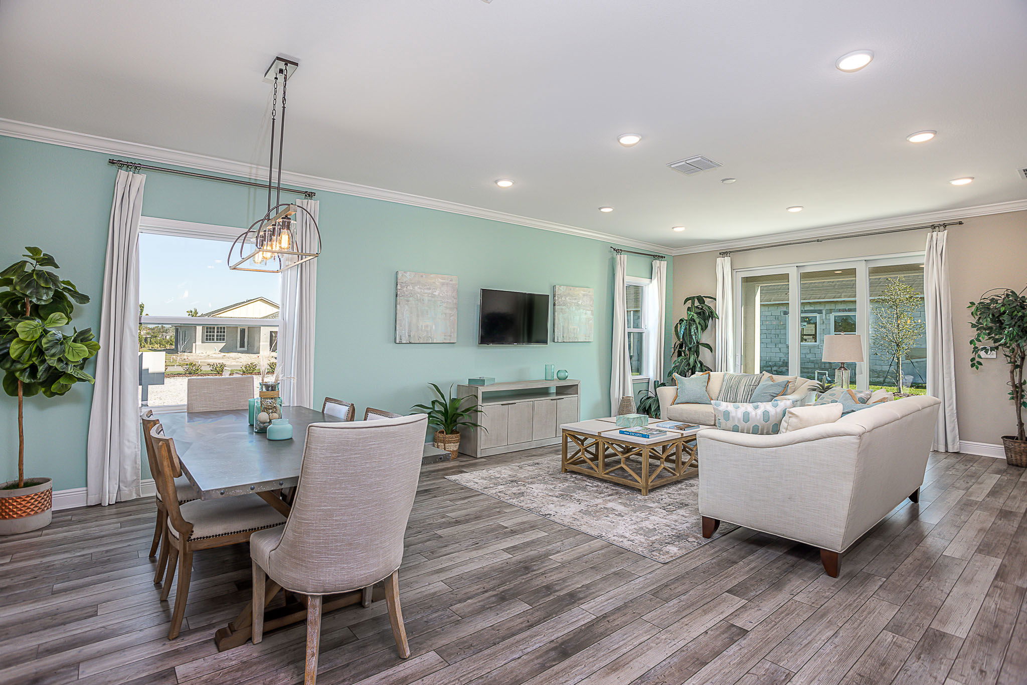 Modern open-concept living and dining area with light turquoise walls, wood flooring, and contemporary furnishings.
