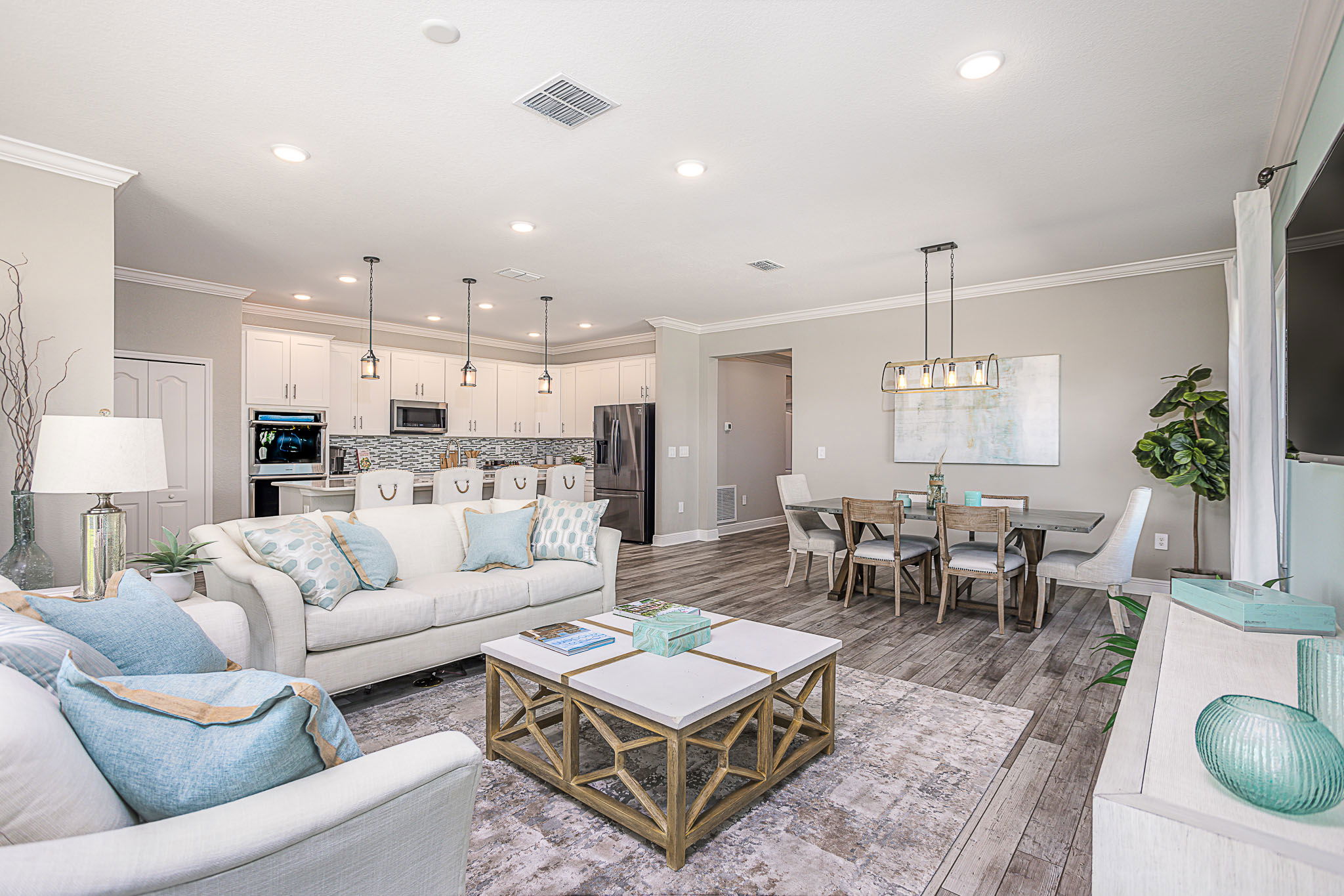 Elegant open-concept living room and kitchen with modern decor, light colors, and stylish furniture.