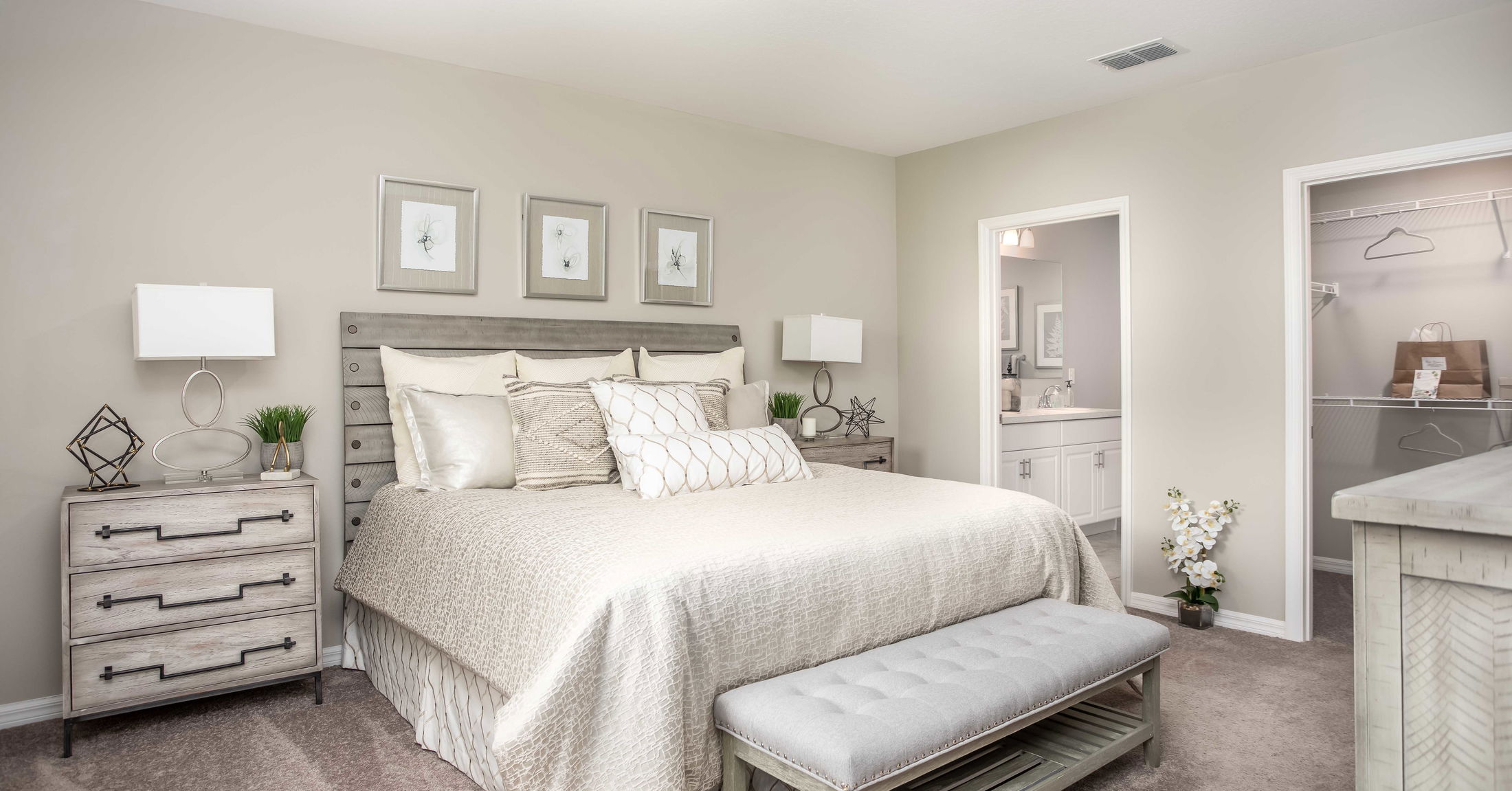 Modern, stylish bedroom with beige walls, a cozy bed, matching nightstands, and a walk-in closet.