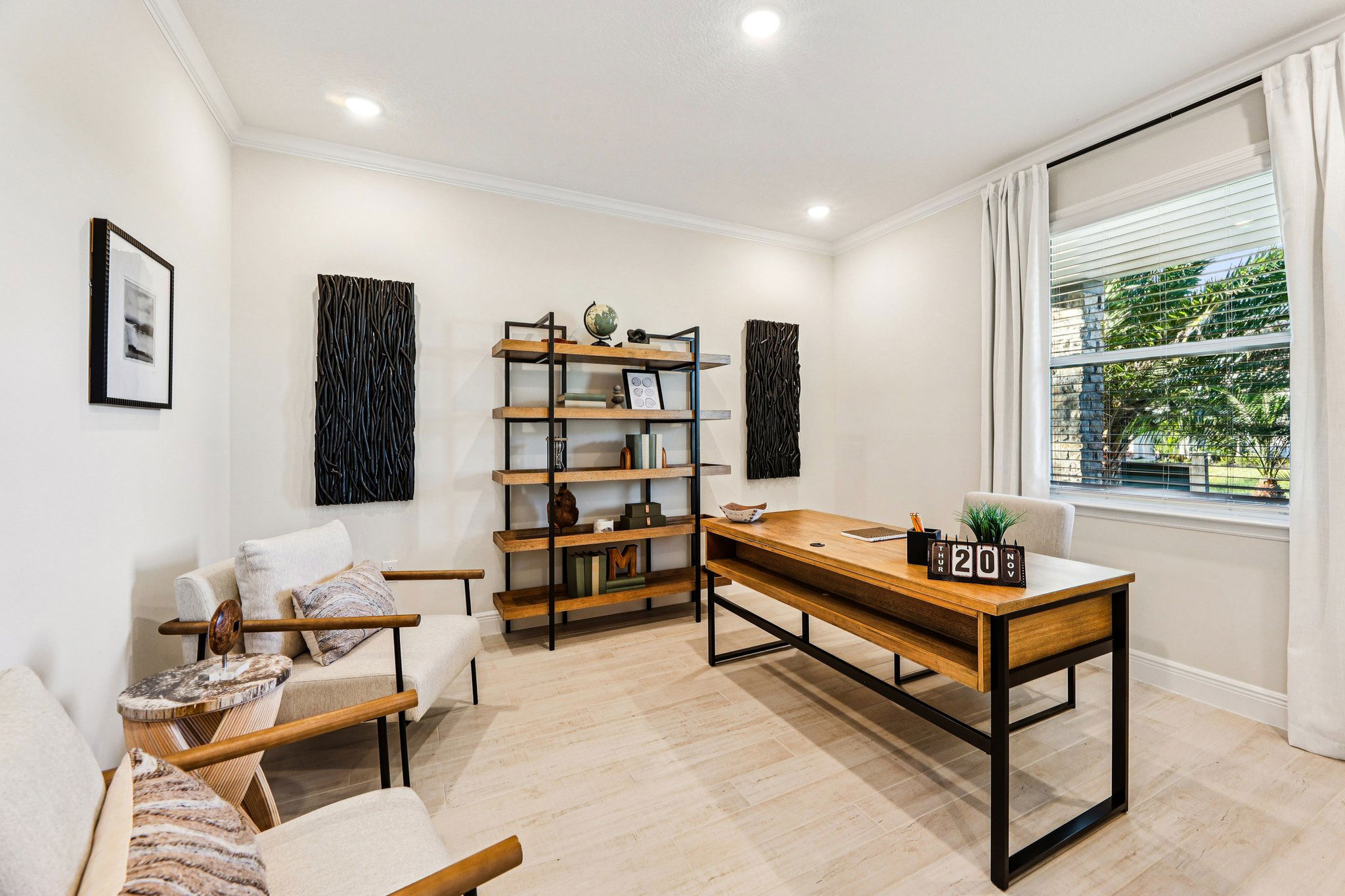 Modern home office with wooden desk, open shelving, and cozy seating, accented by large window and neutral decor.