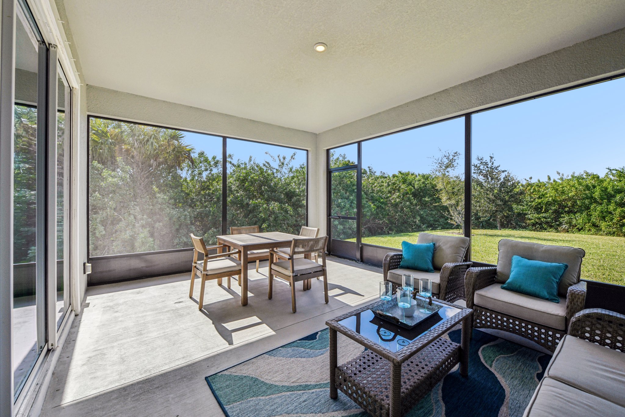 Stylish screened patio with cozy seating, decorative rug, and garden view for relaxed outdoor living.