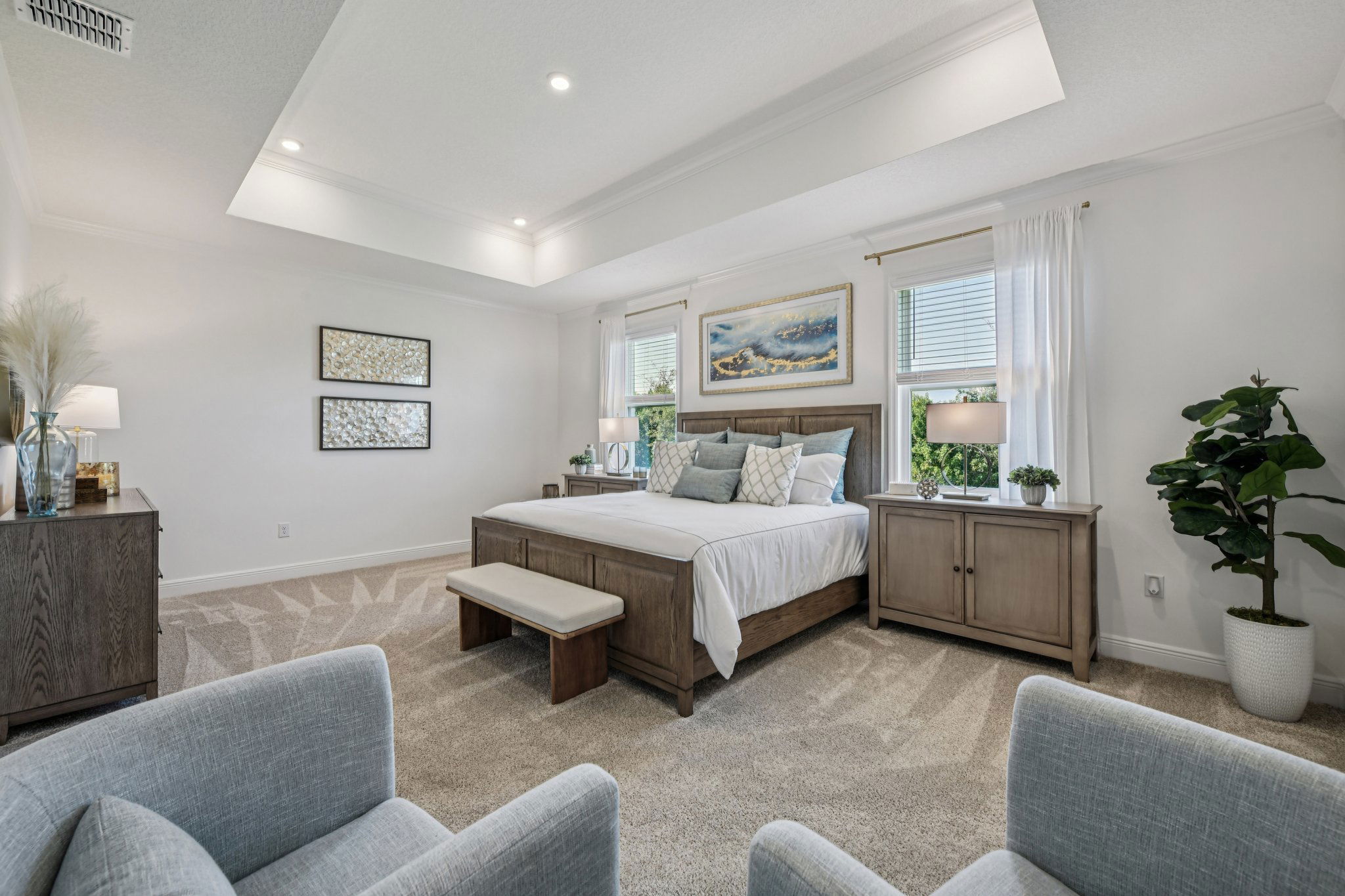 Luxurious modern bedroom featuring a king-sized bed with wooden furniture, neutral decor, and abundant natural light from large windows.